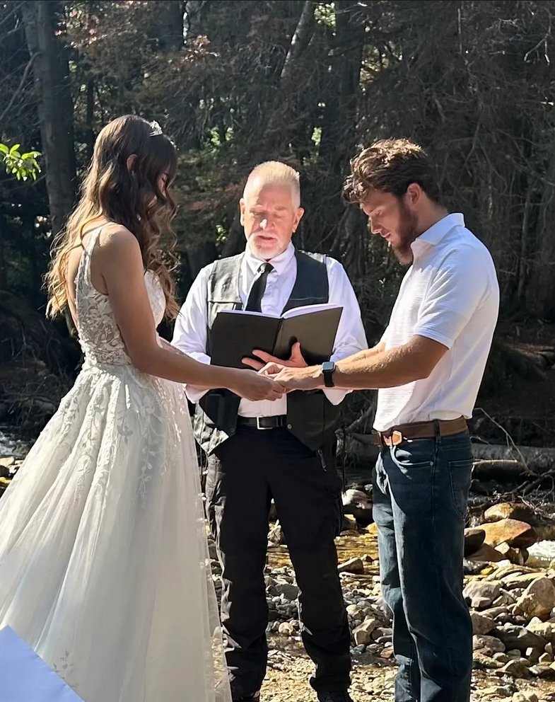 Brad Wright officiating a forest elopement as the bride and groom hold hands