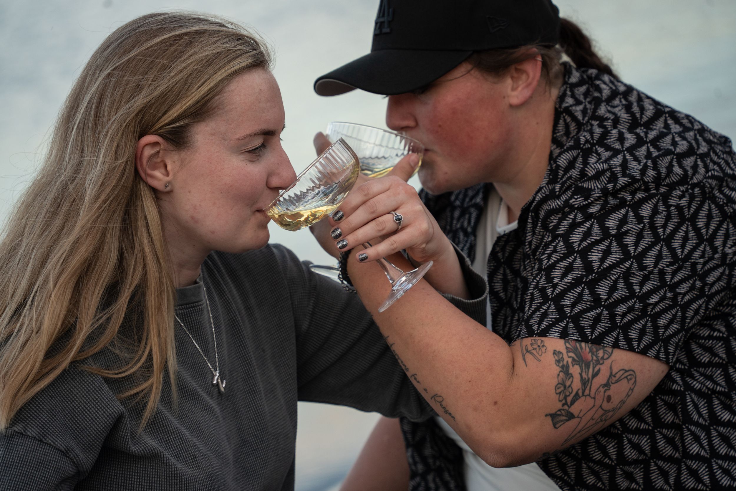 wlw couple sharing champagne with intehooked arms looking into each other's eyes and smiling