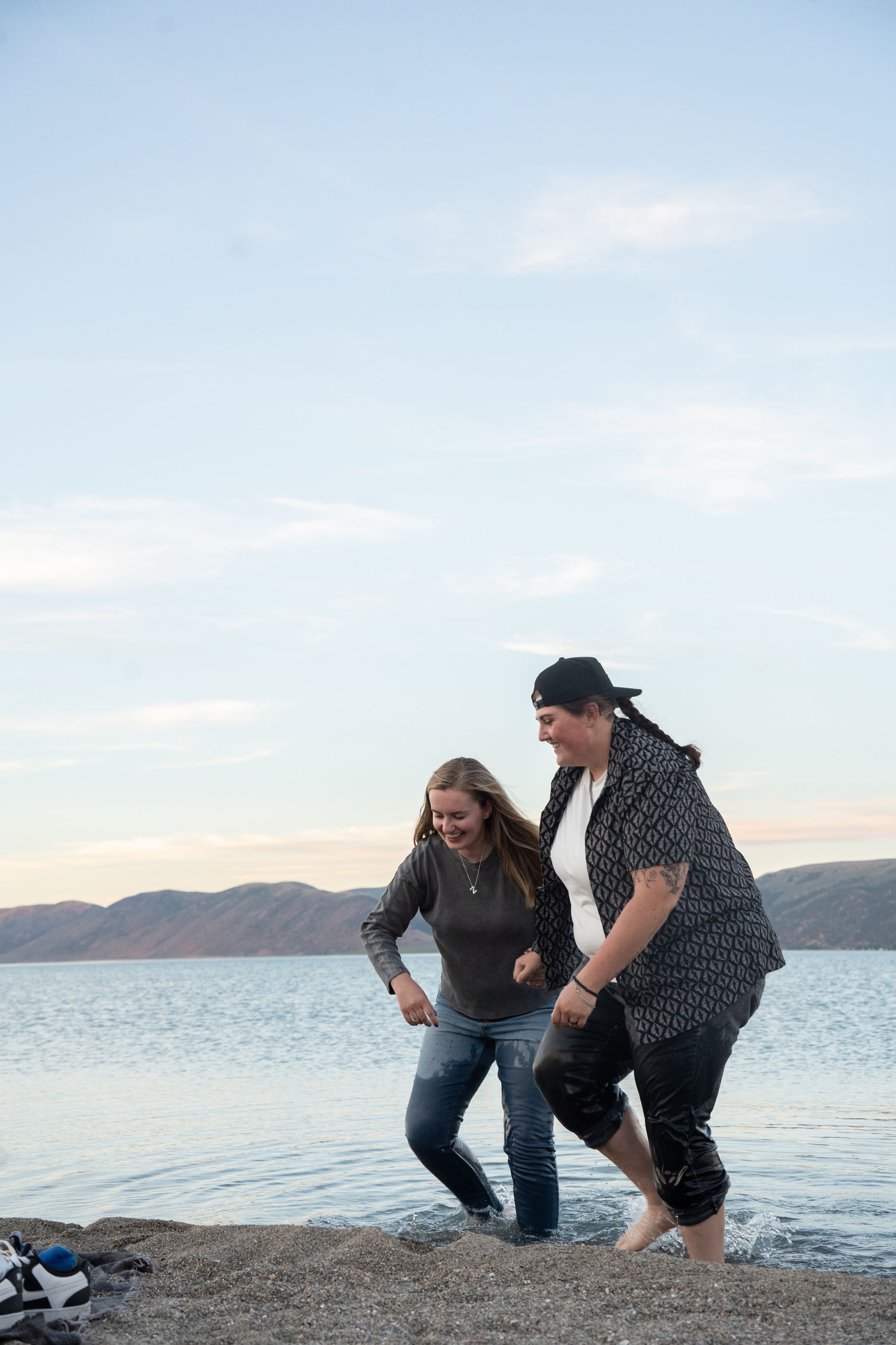 lesbian couple laughing and running through bear lake after their proposal