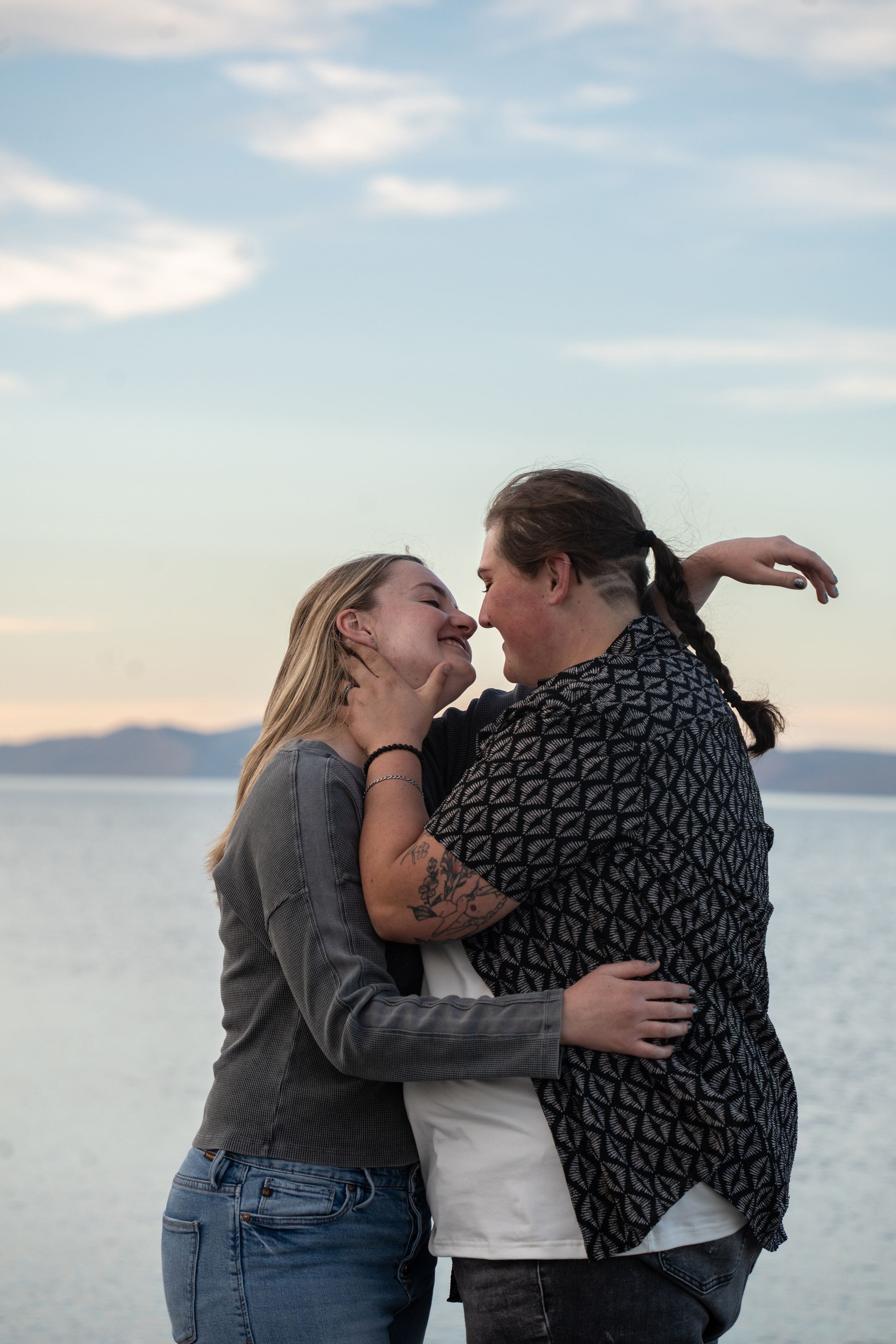 woman holding her girlfriend's face in a romantic embrace with bear lake and mountains in the background