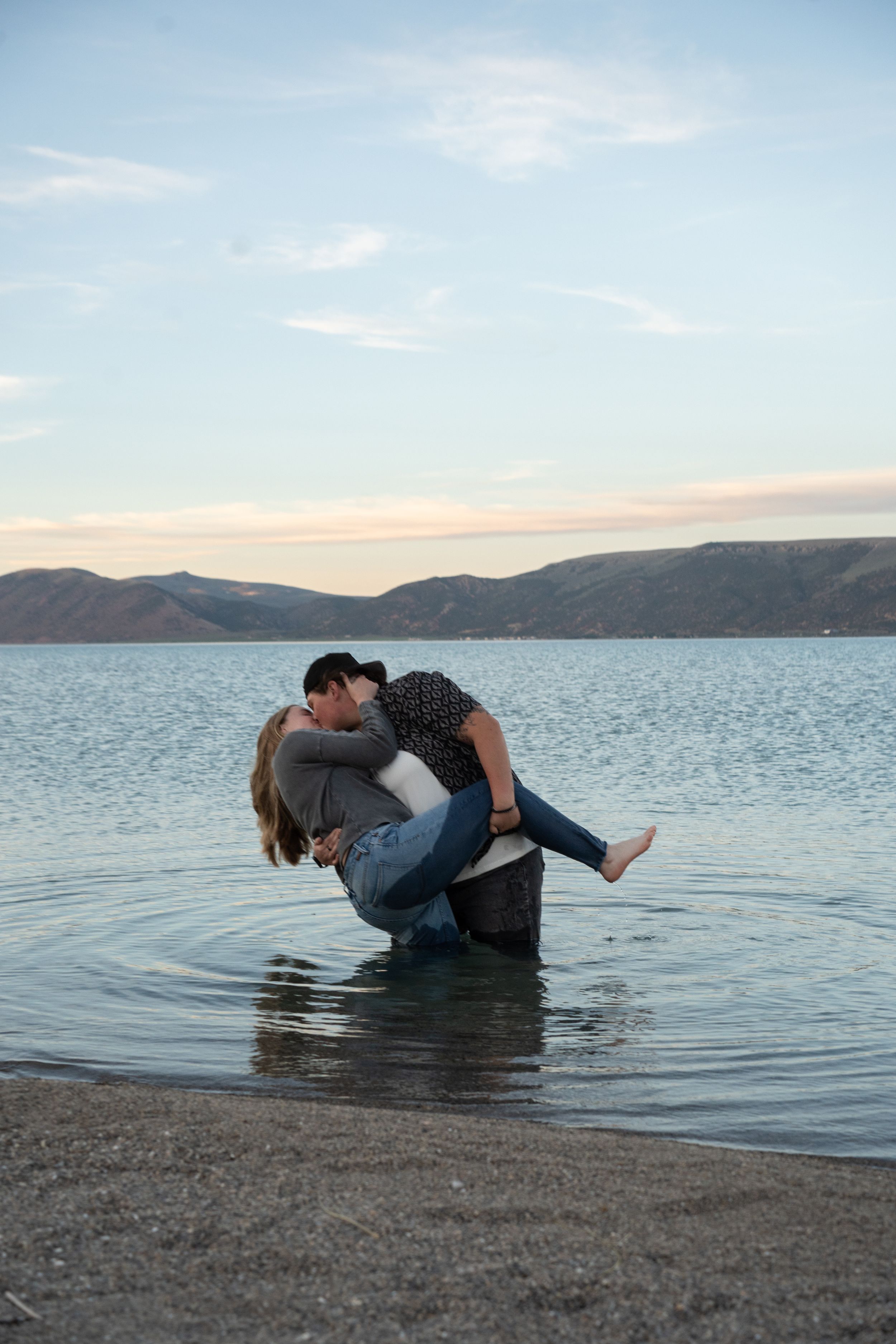 lesbian couple kissing and leaning over in the shallow water of bear lake