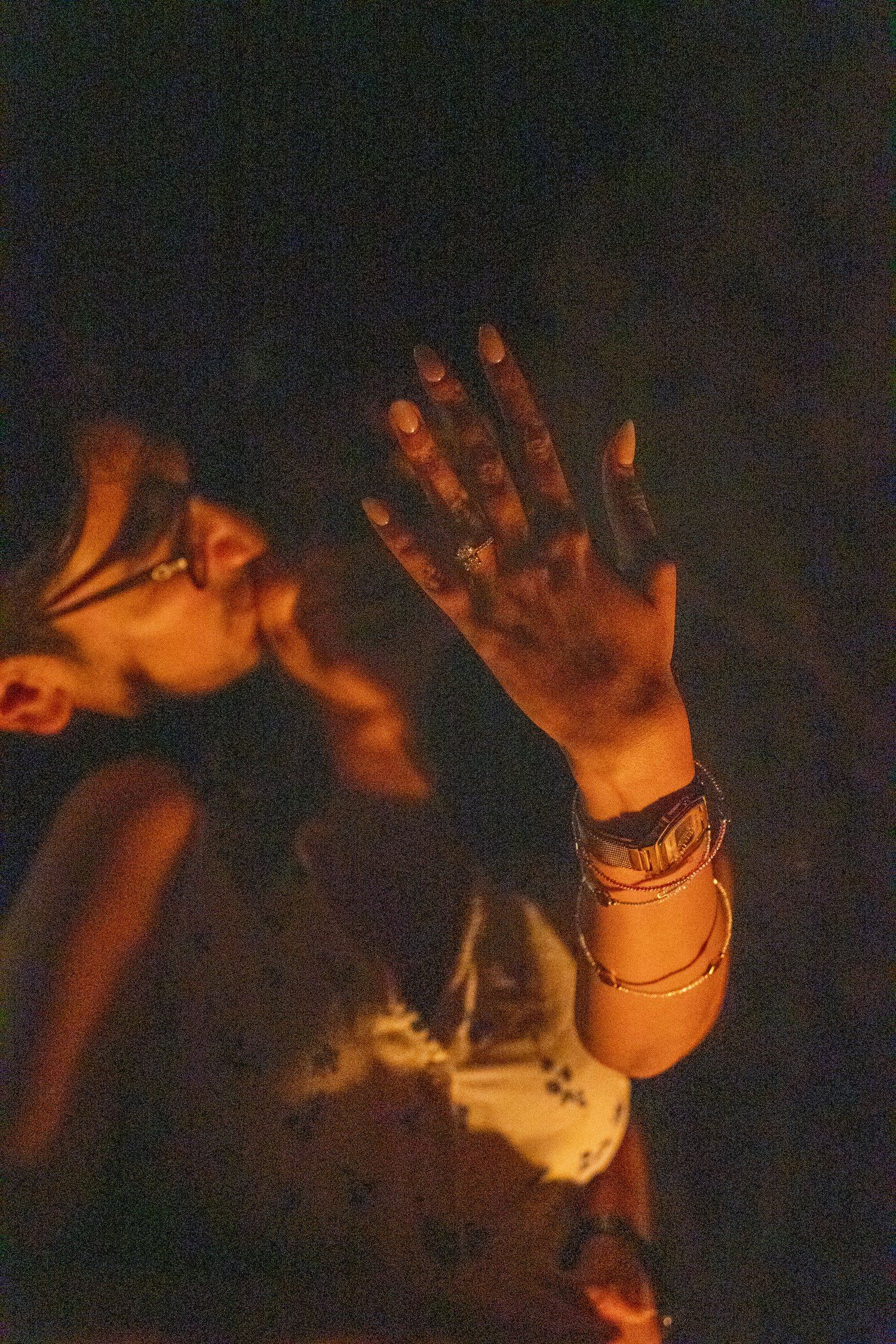 Close-up of a man kissing his newly engaged partner's hand by campfire light, her new engagement ring glowing in the firelight