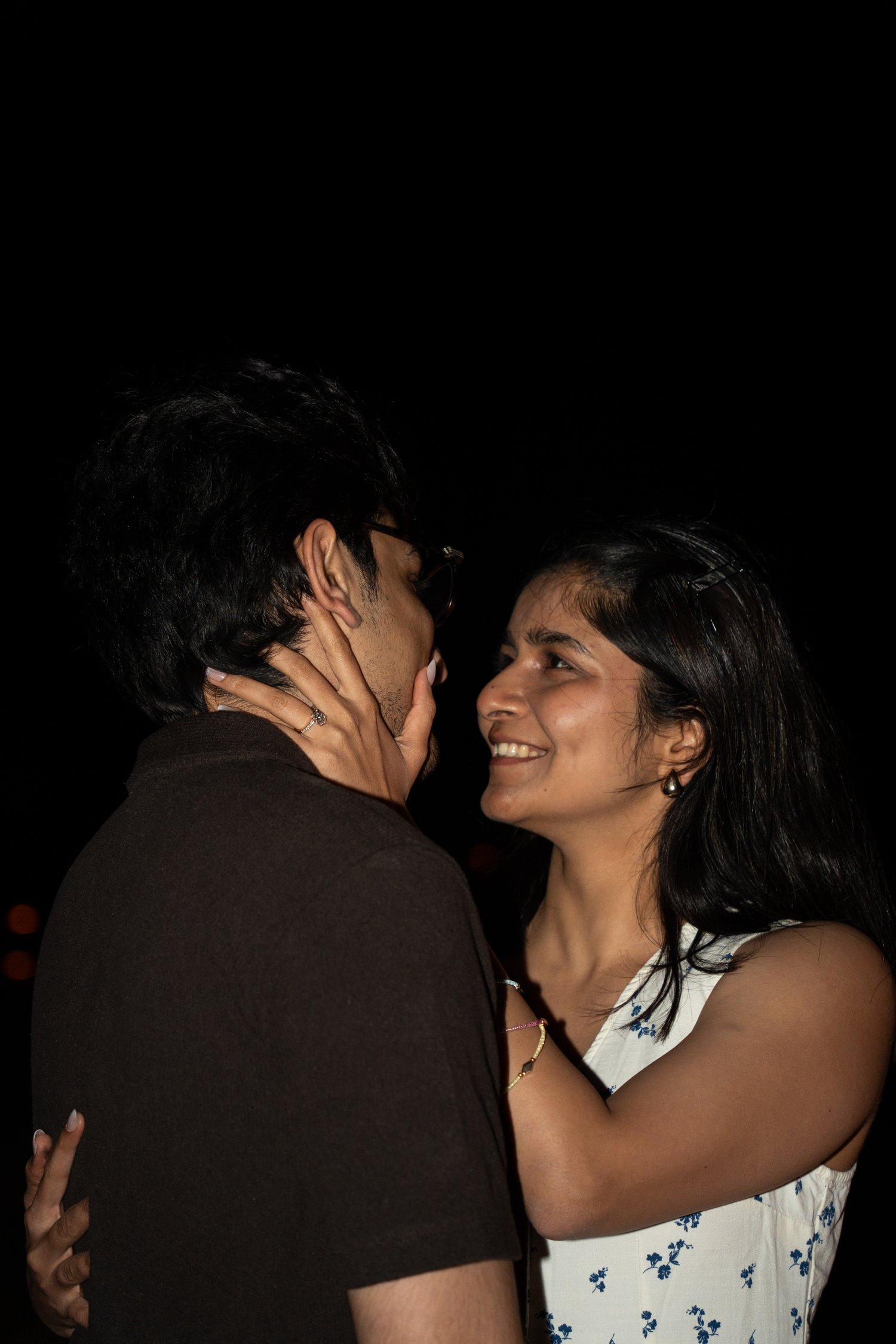 Newly engaged woman smiling with her hand on her partner's face moments after he proposed