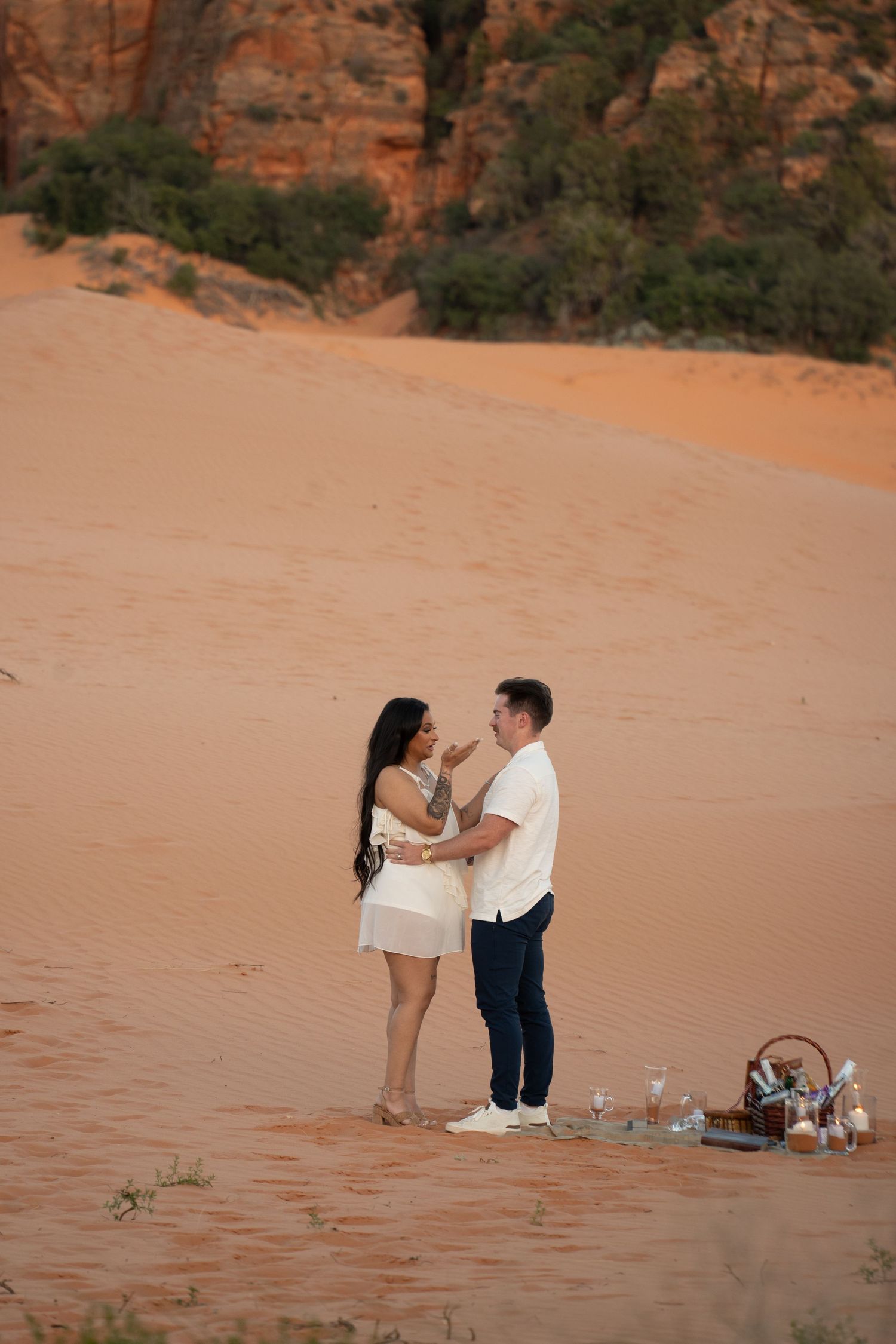 Couple embracing on red sand dunes near Kanab, Utah at golden hour, another southern Utah image, not from Zion, used to represent the red-rock desert aesthetic.