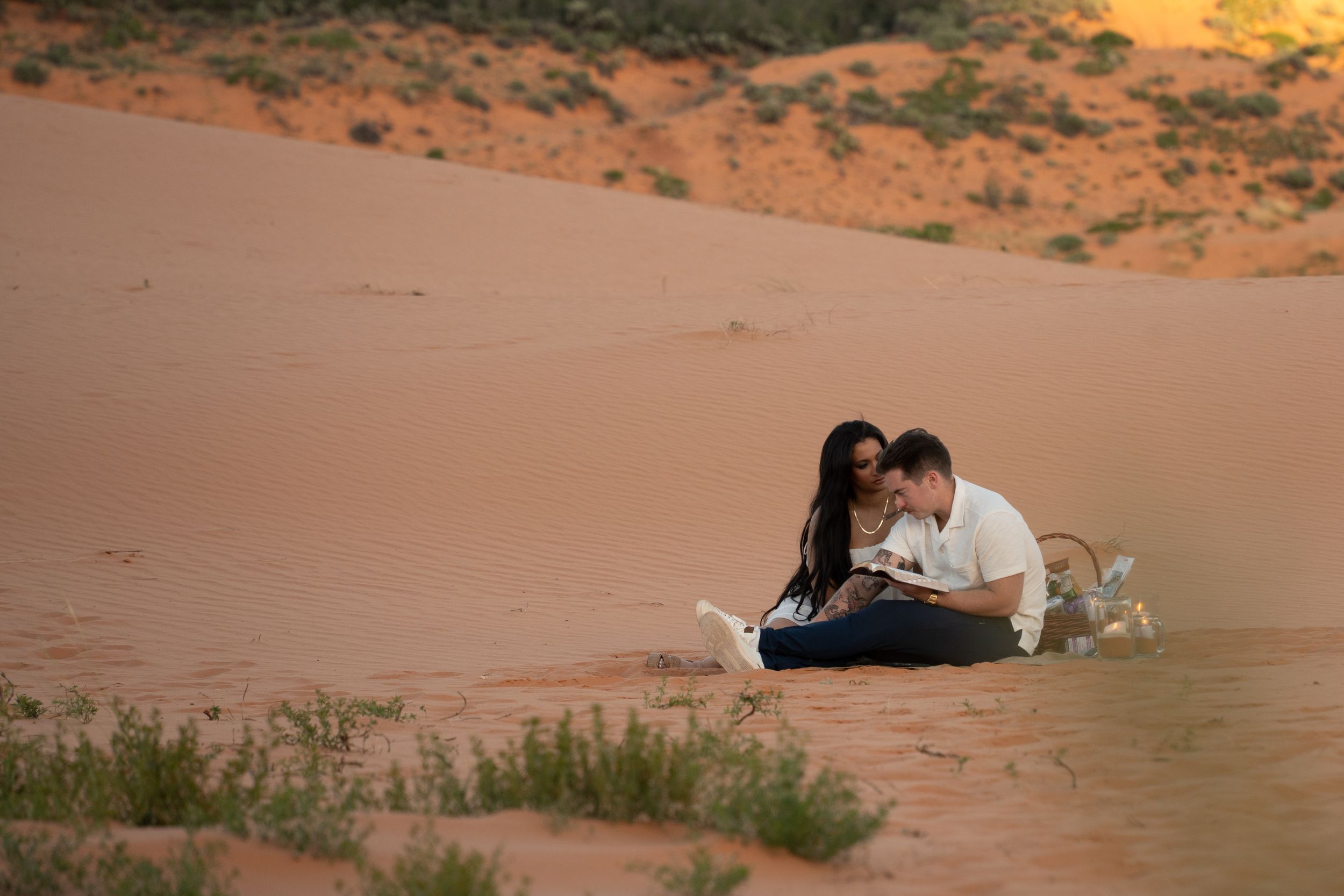 Couple celebrating an engagement on red desert sand dunes in southern Utah, representative of Jade's red-rock proposal photography style.