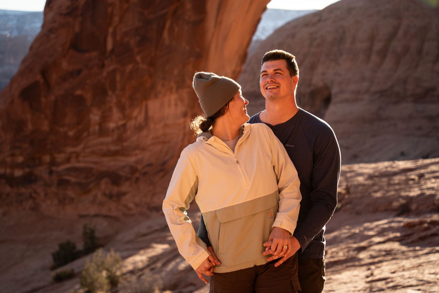 Couple smiling and embracing at sunset in a red rock canyon