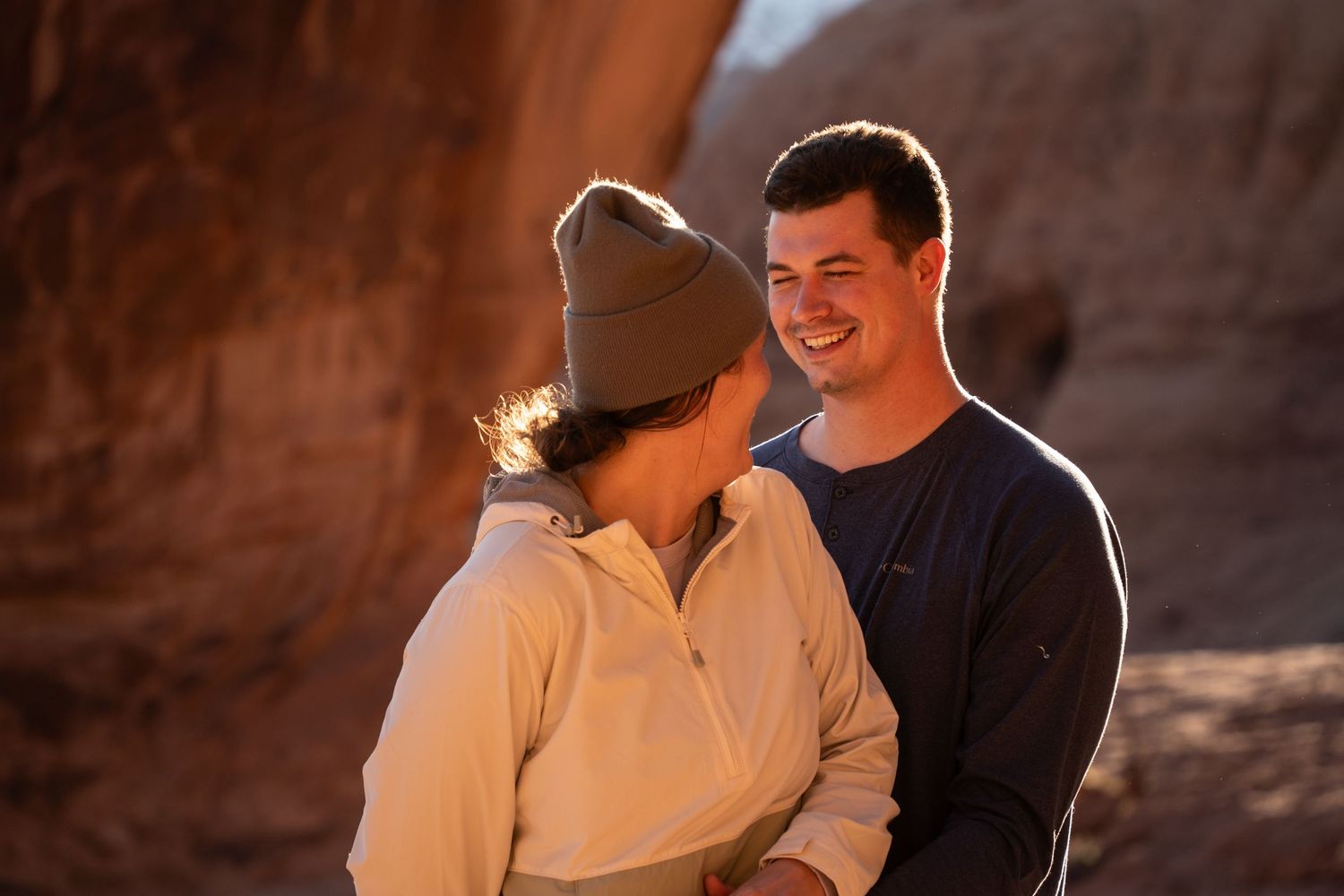 Couple smiling and sharing a romantic moment outdoors on a red rock hiking trail