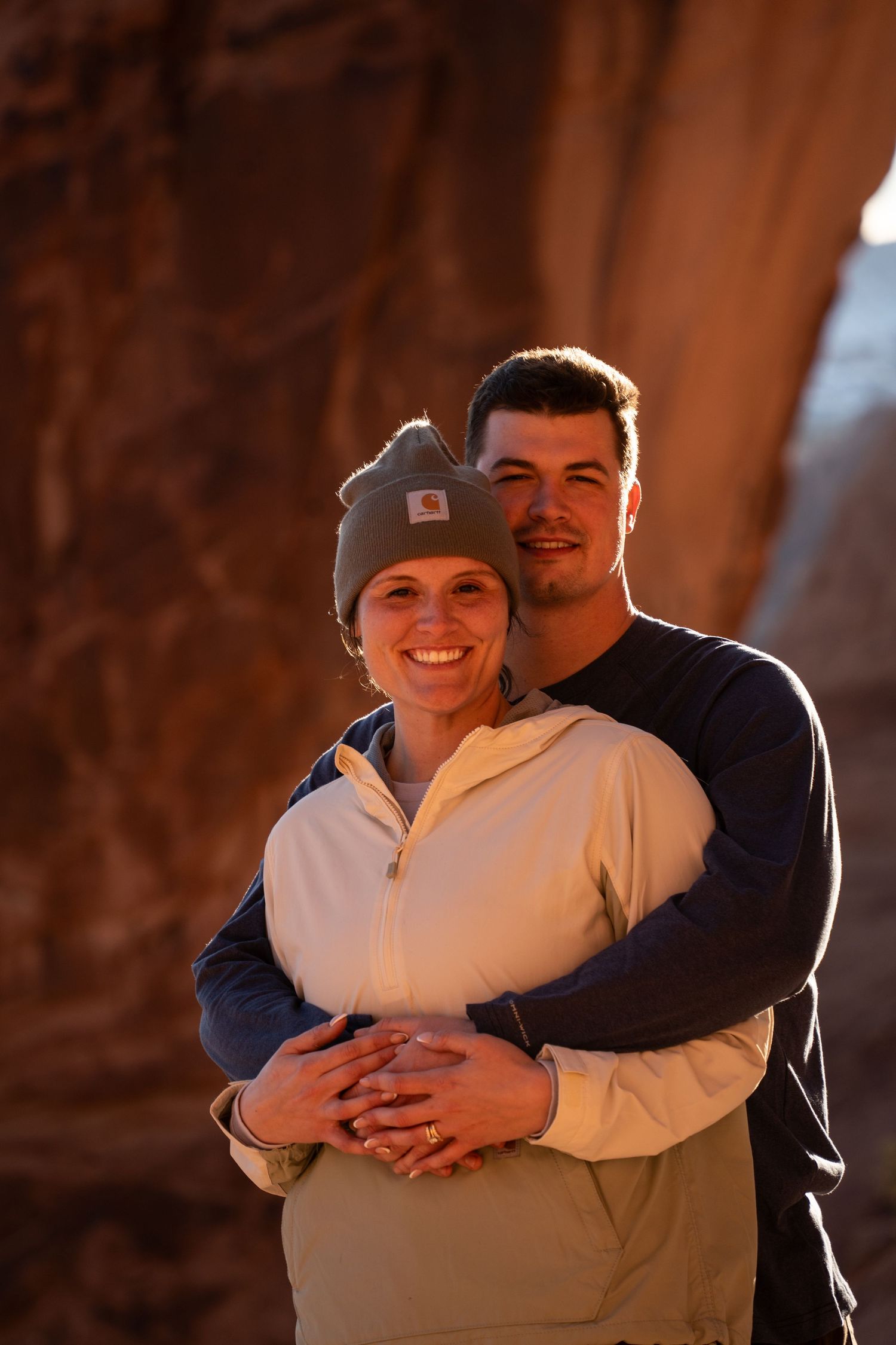 Couple embracing and smiling in a warm red rock canyon glow