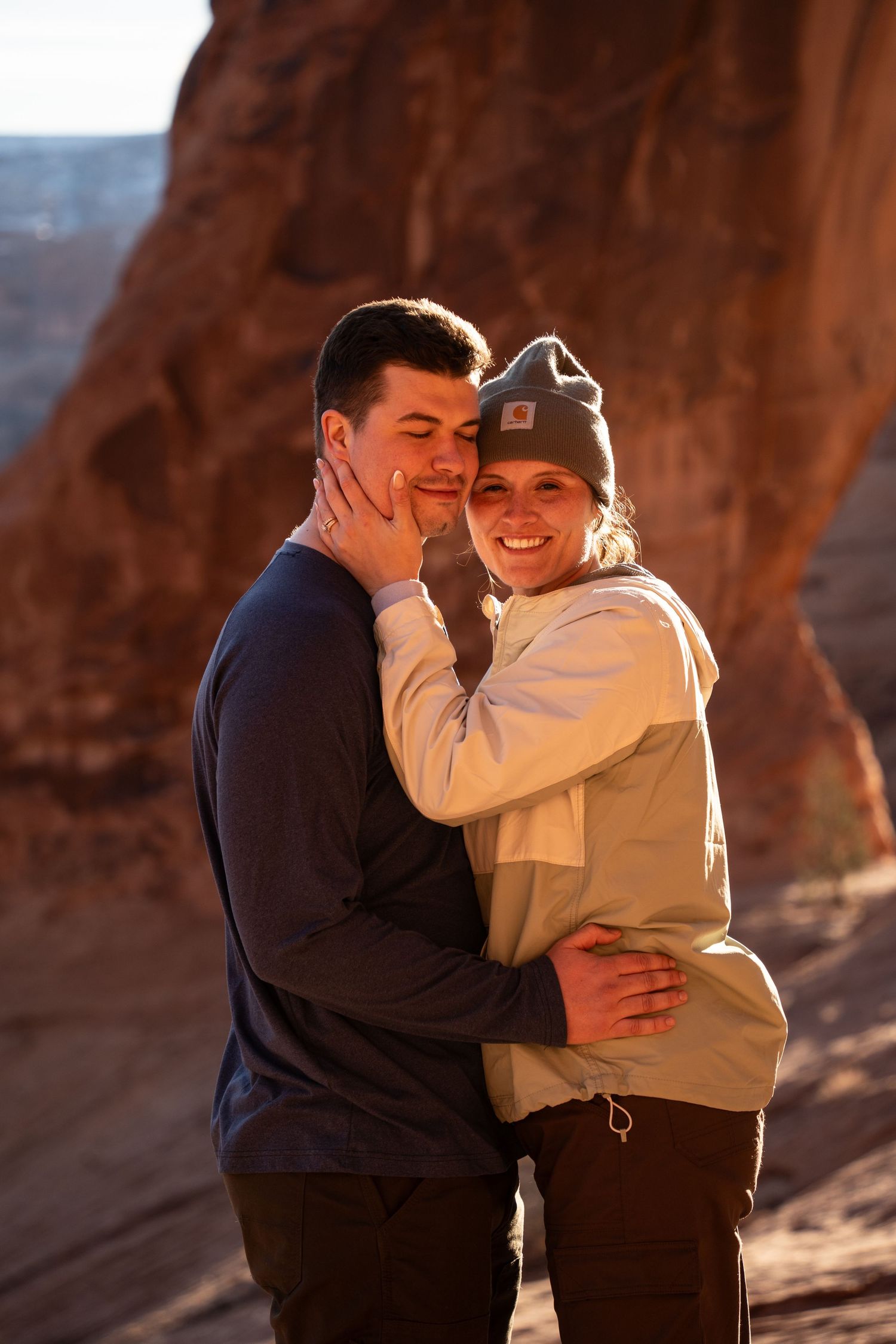 Couple embracing and smiling at sunset near red rock formations