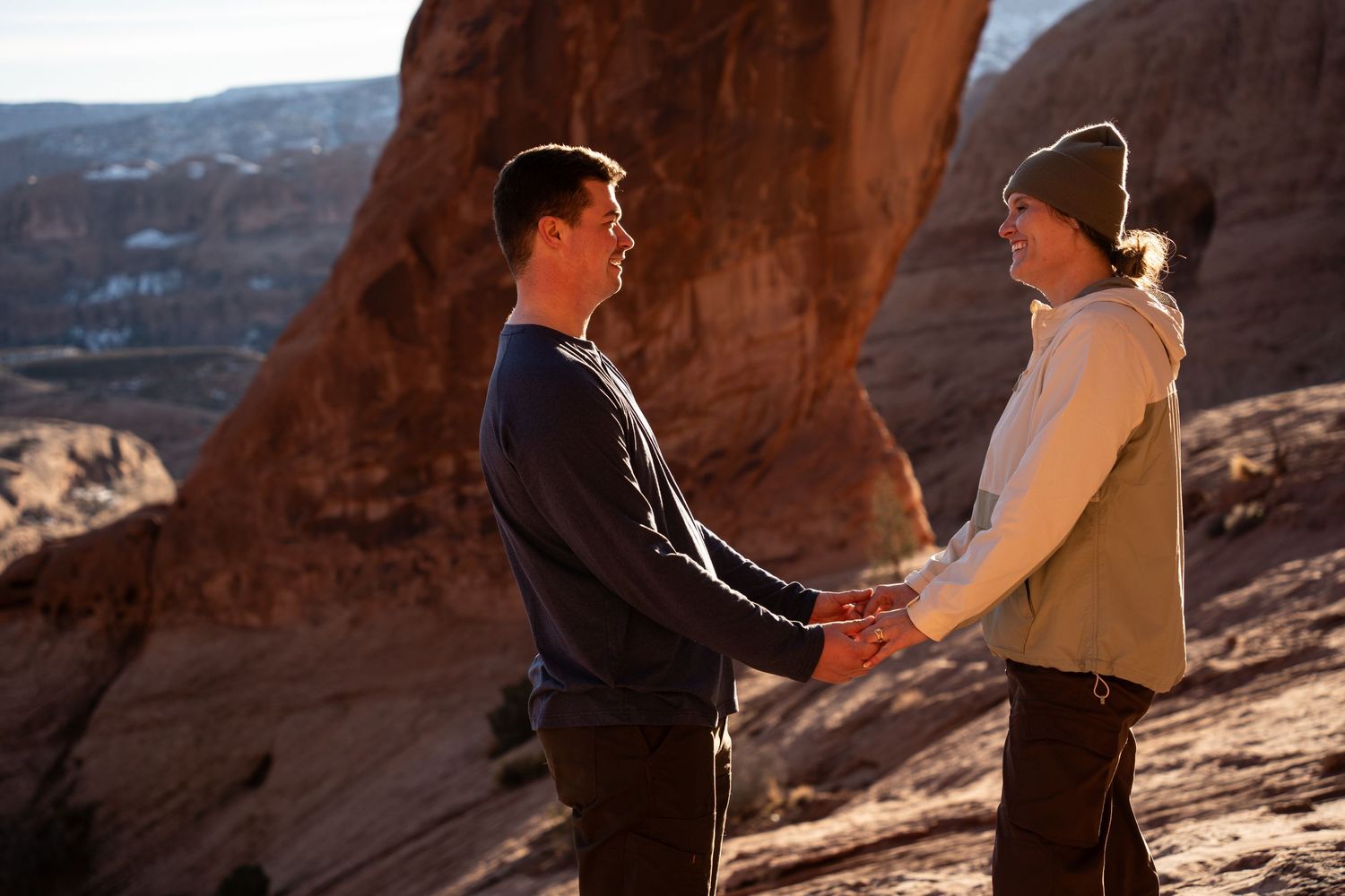 Couple holding hands facing each other on a red rock overlook