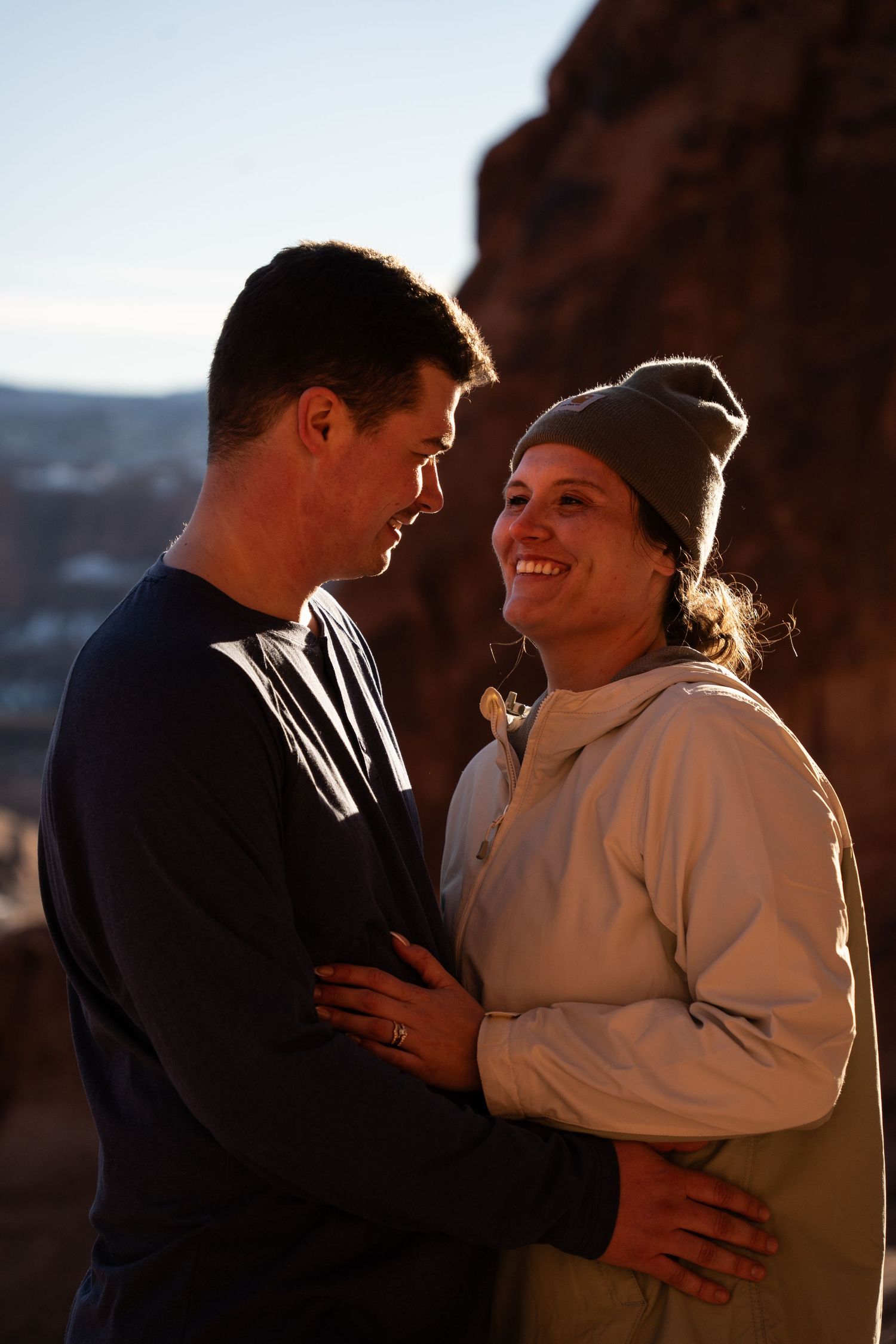 Couple embracing and smiling at sunset near red rock formations