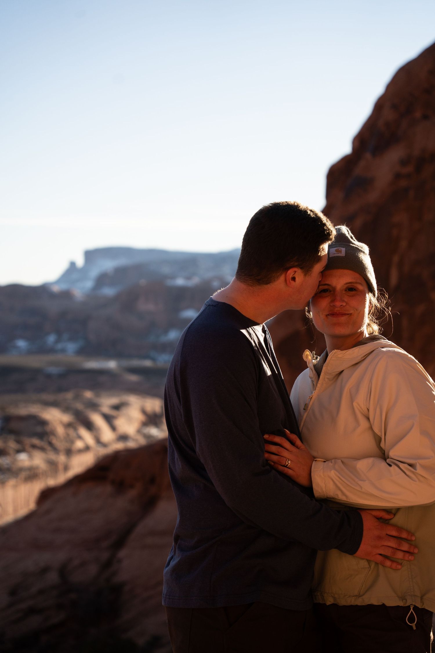 Couple embracing on rocky desert overlook at golden hour