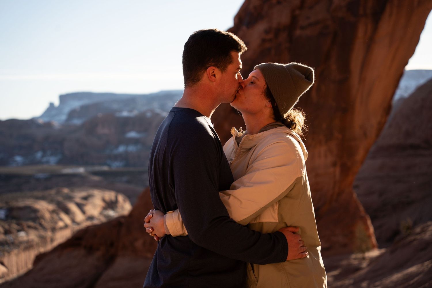 Couple sharing a romantic kiss in front of red rock cliffs