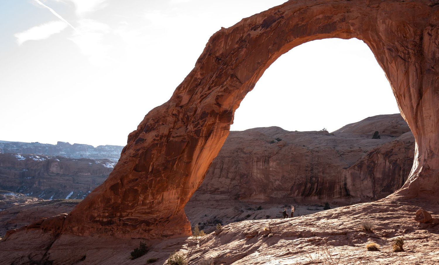 Massive red sandstone arch frames canyon landscape at golden hour