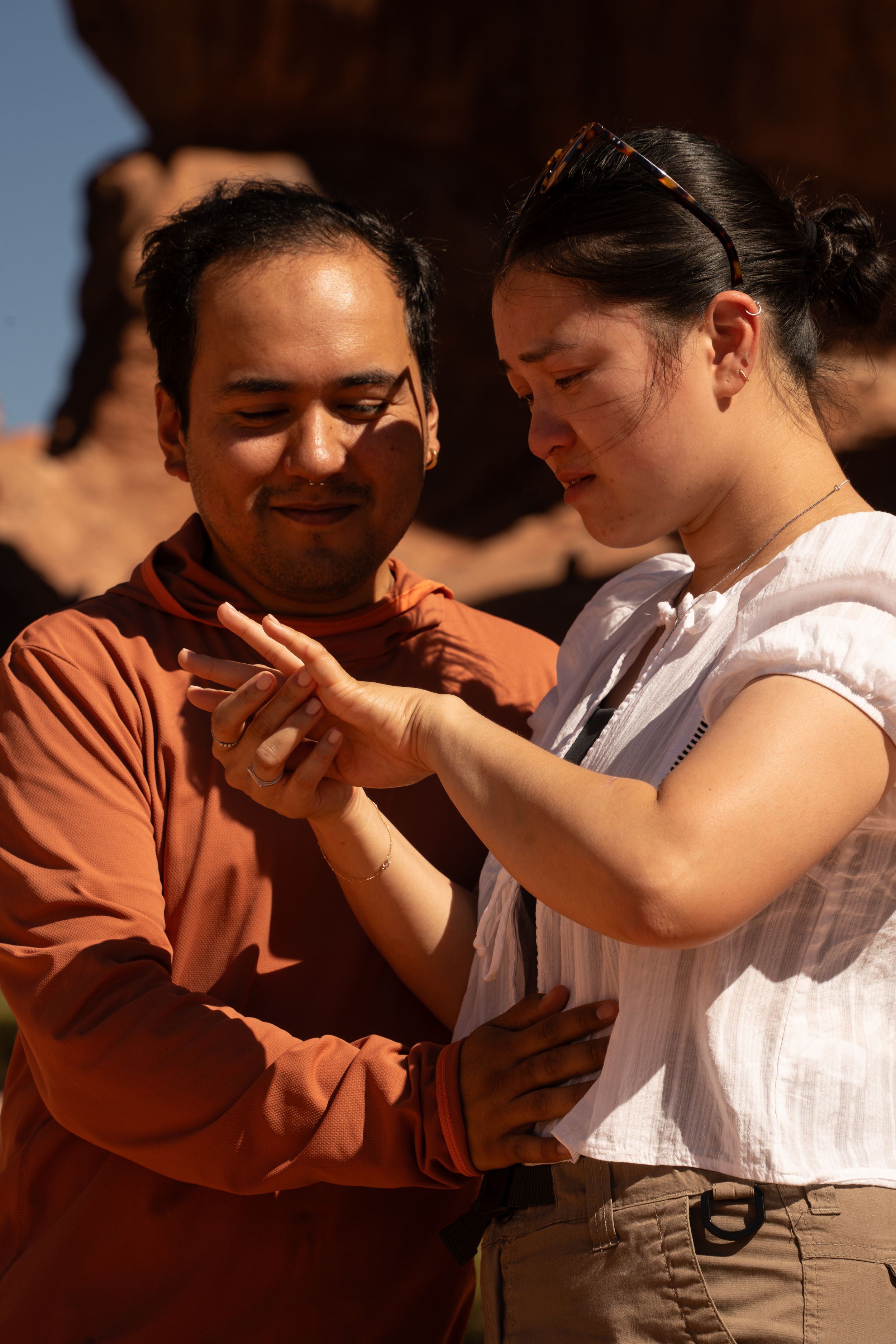 A man and woman admire her engagement ring after his romantic hiking proposal in Arches National park