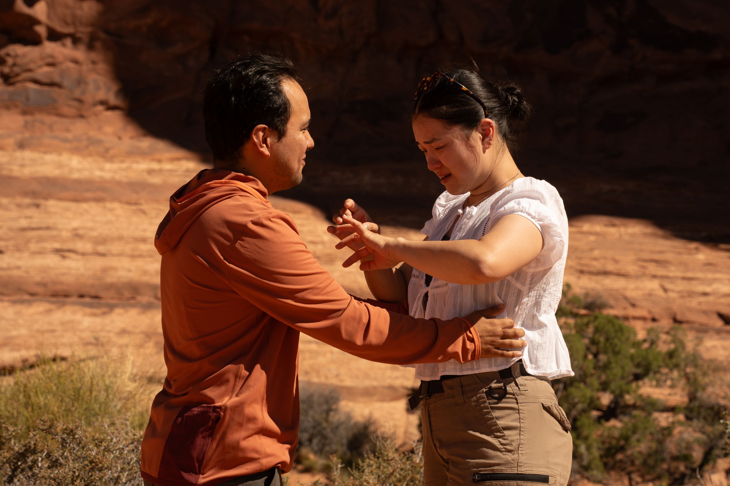 Two people sharing an intimate moment outdoors near red rock canyon formations in a desert landscape.