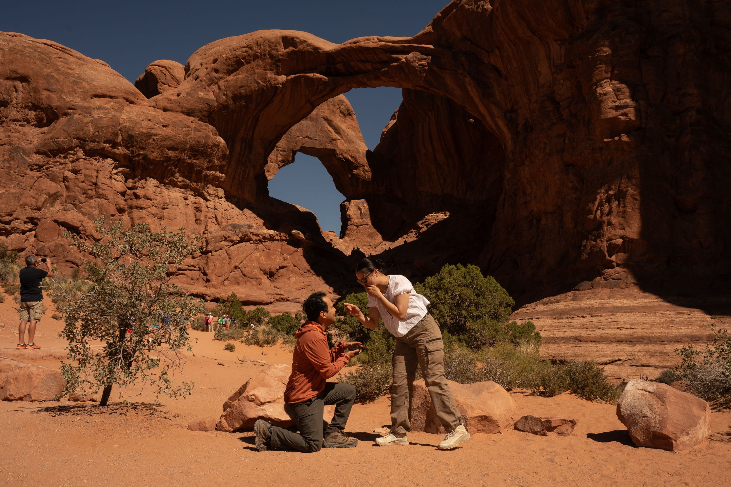 Couple sharing a romantic proposal moment at Double Arch in Arches National Park, Utah.
