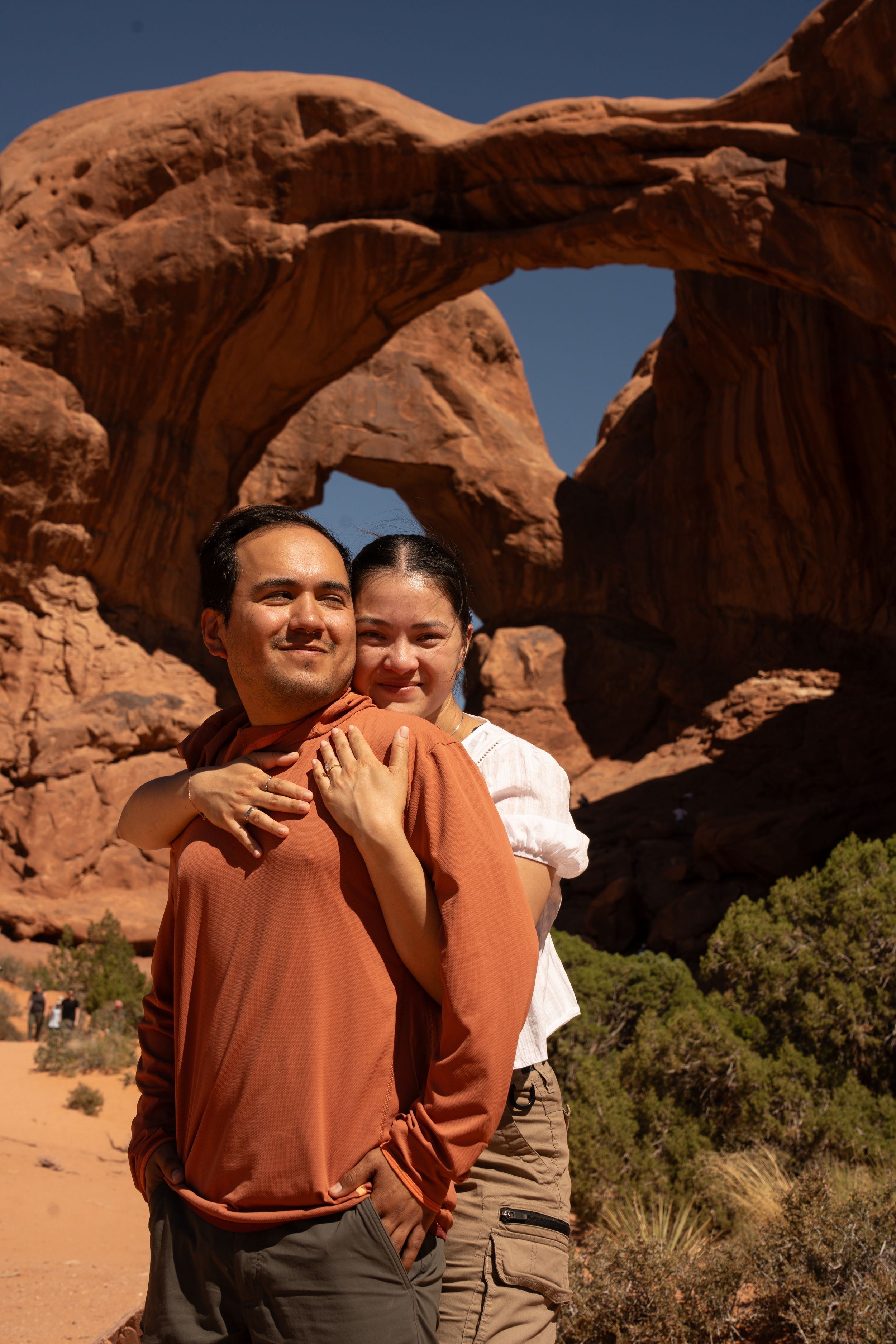 Couple posing together in front of a natural sandstone arch at Arches National Park, Utah.