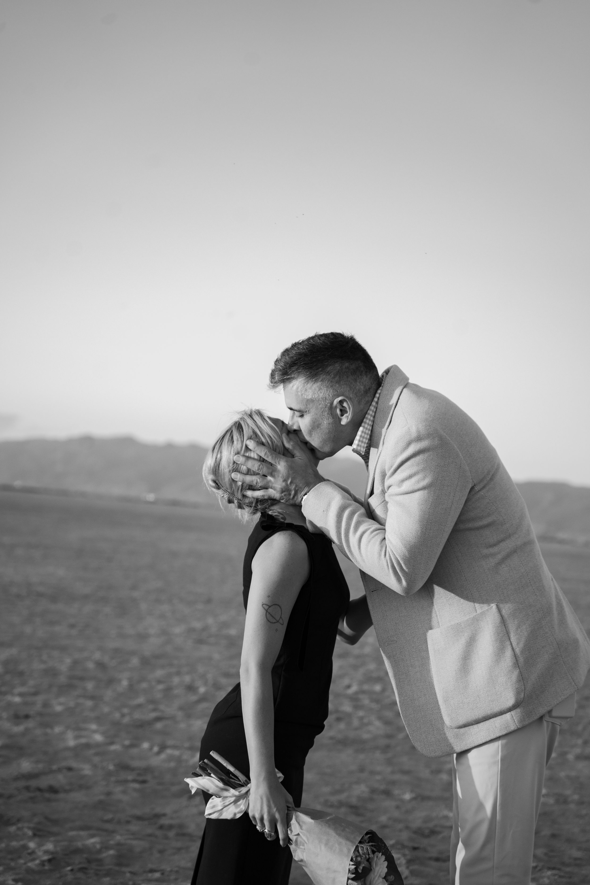 Black and white photo of newly engaged couple sharing a romantic kiss in salt frats of great saltair