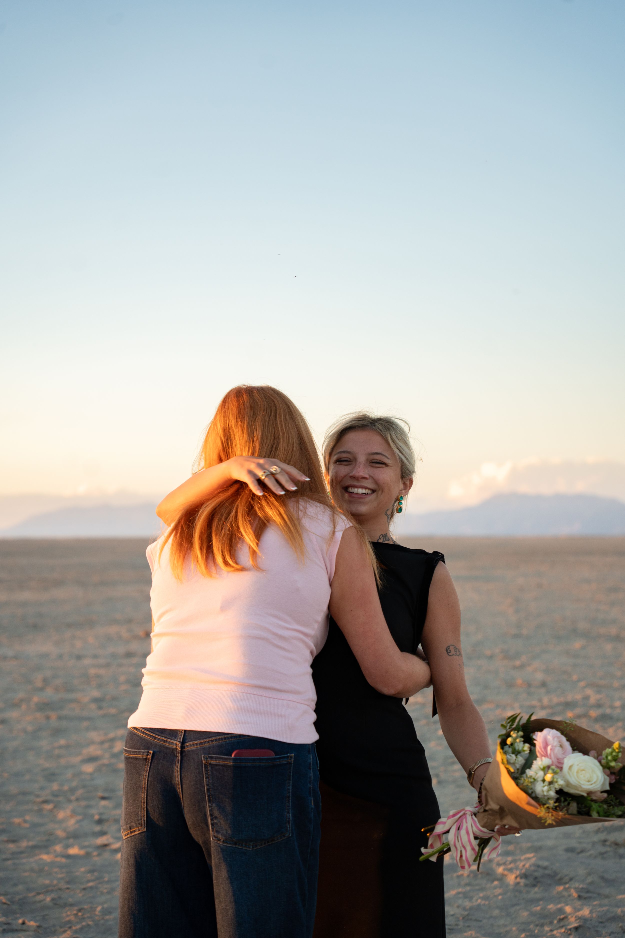 newly engaged woman with her best friend, holding a bouquet of flowers, celebrating her engagement