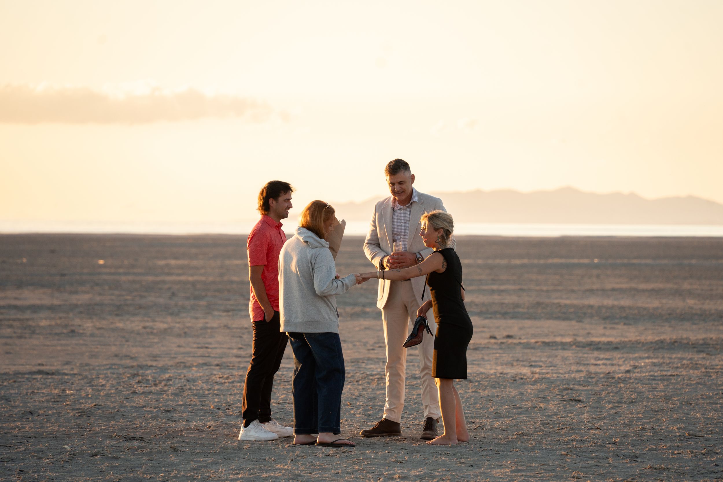 woman exclaiming over her engagement ring and showing her friends her new ring after her boyfriend's proposal on salt flats utah