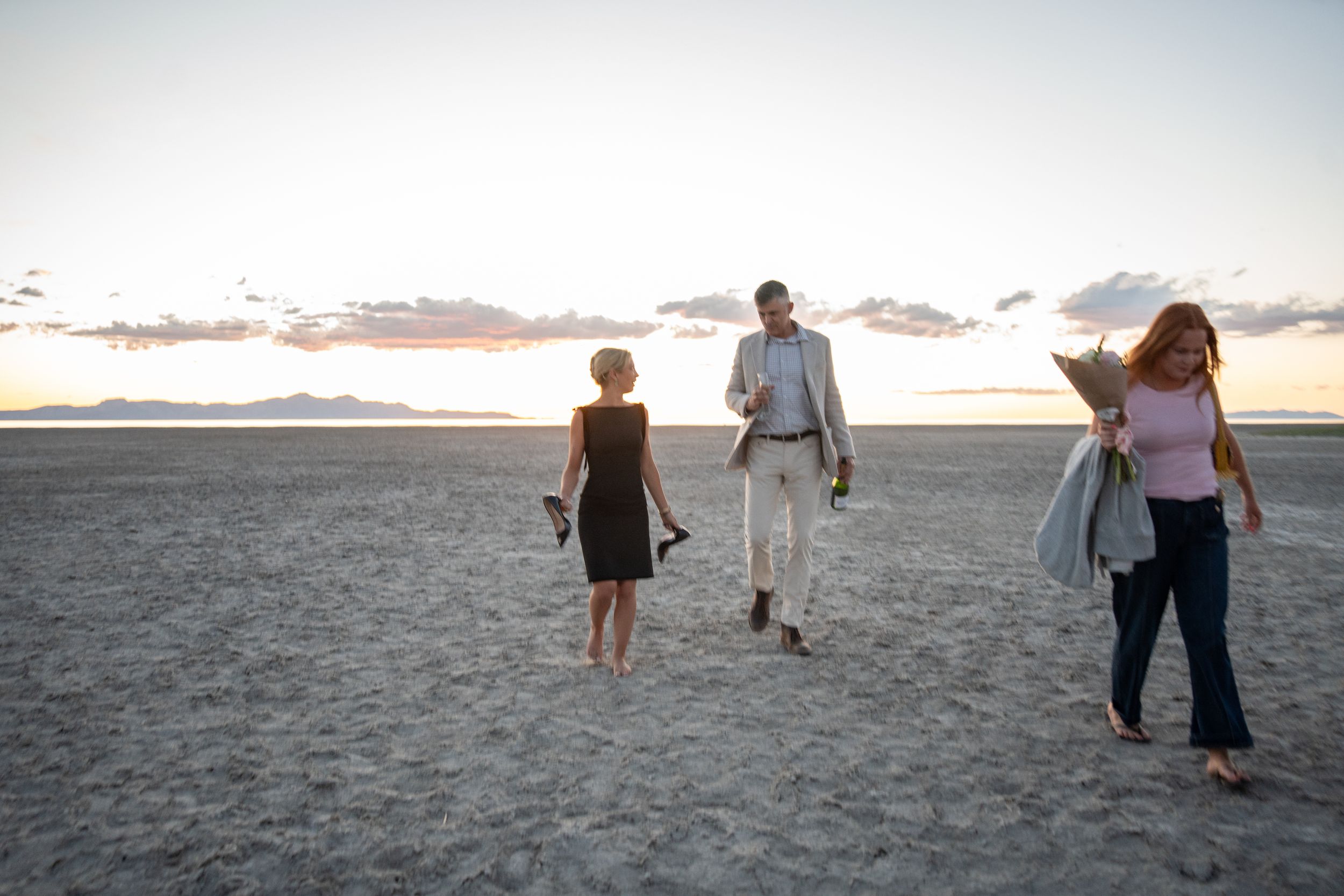 engaged couple and their friend walk along the salt flats after a proposal