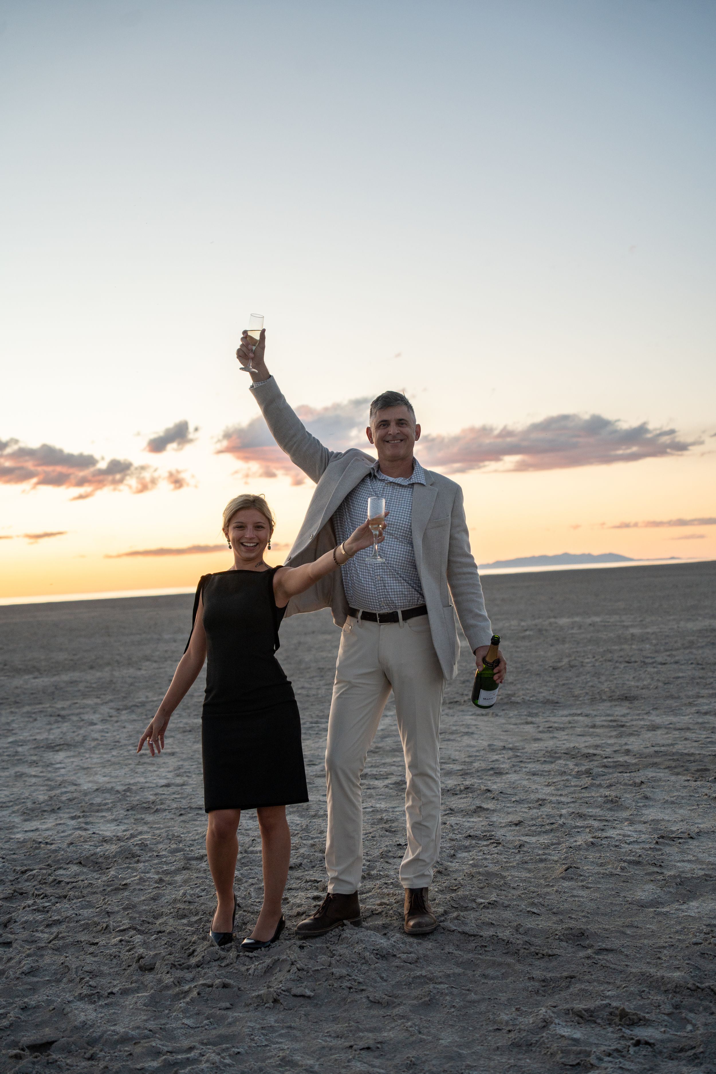 couple raising champagne glasses to celebrate their engagement at the great saltair