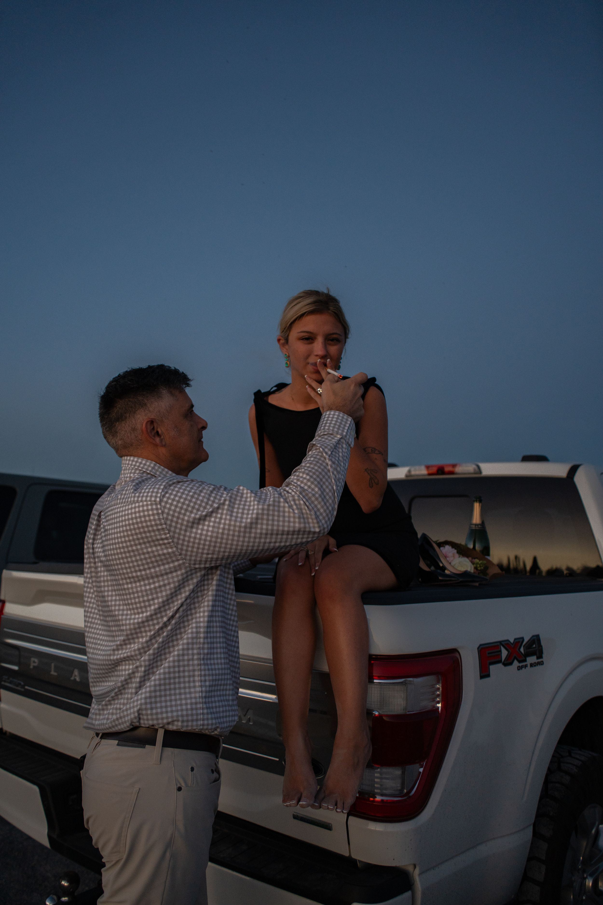 Man and woman sharing a romantic moment at dusk beside a white Ford F-150 pickup truck at great saltair