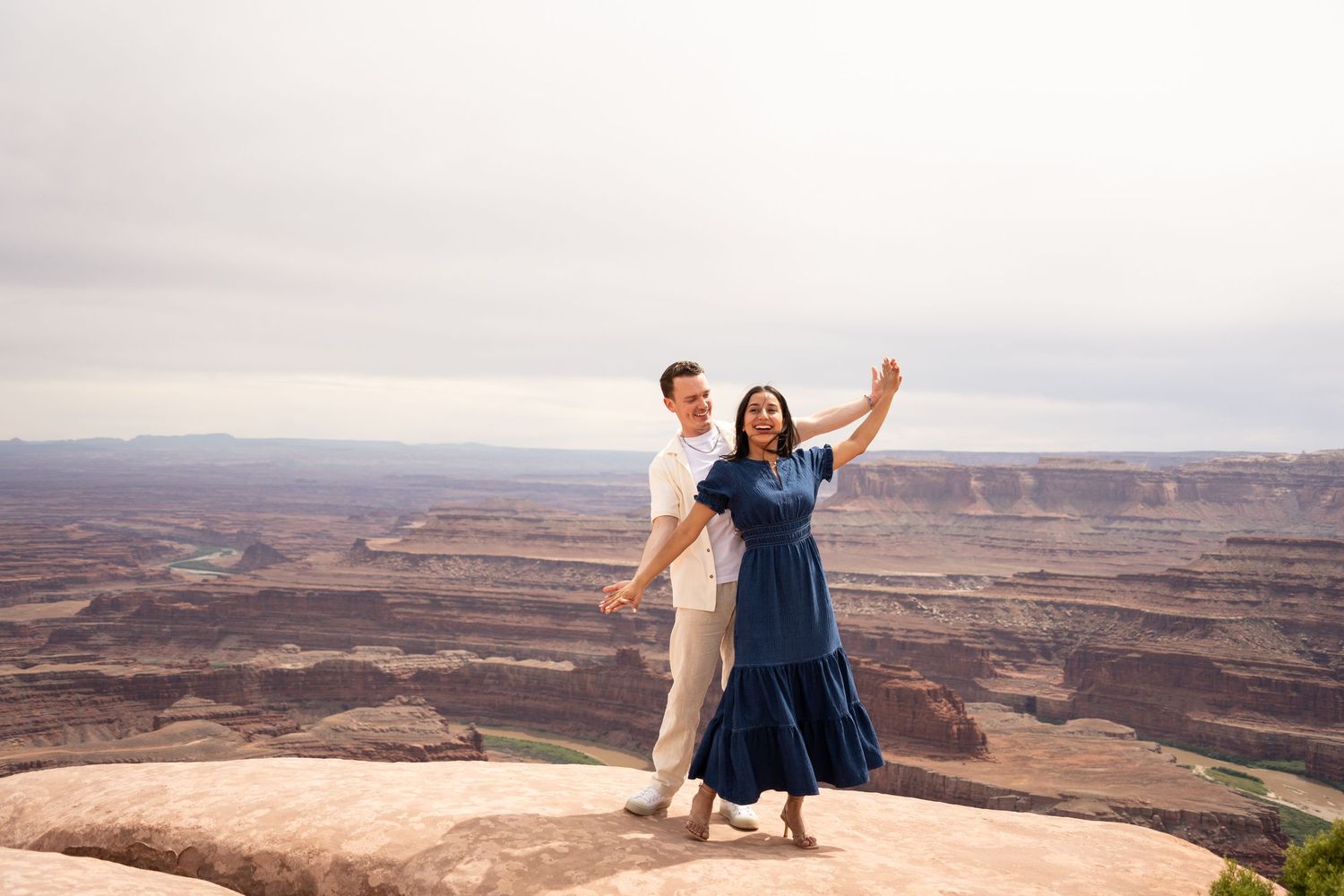 Couple dancing joyfully on a rocky overlook at Dead Horse Point State Park, overlooking Canyonlands