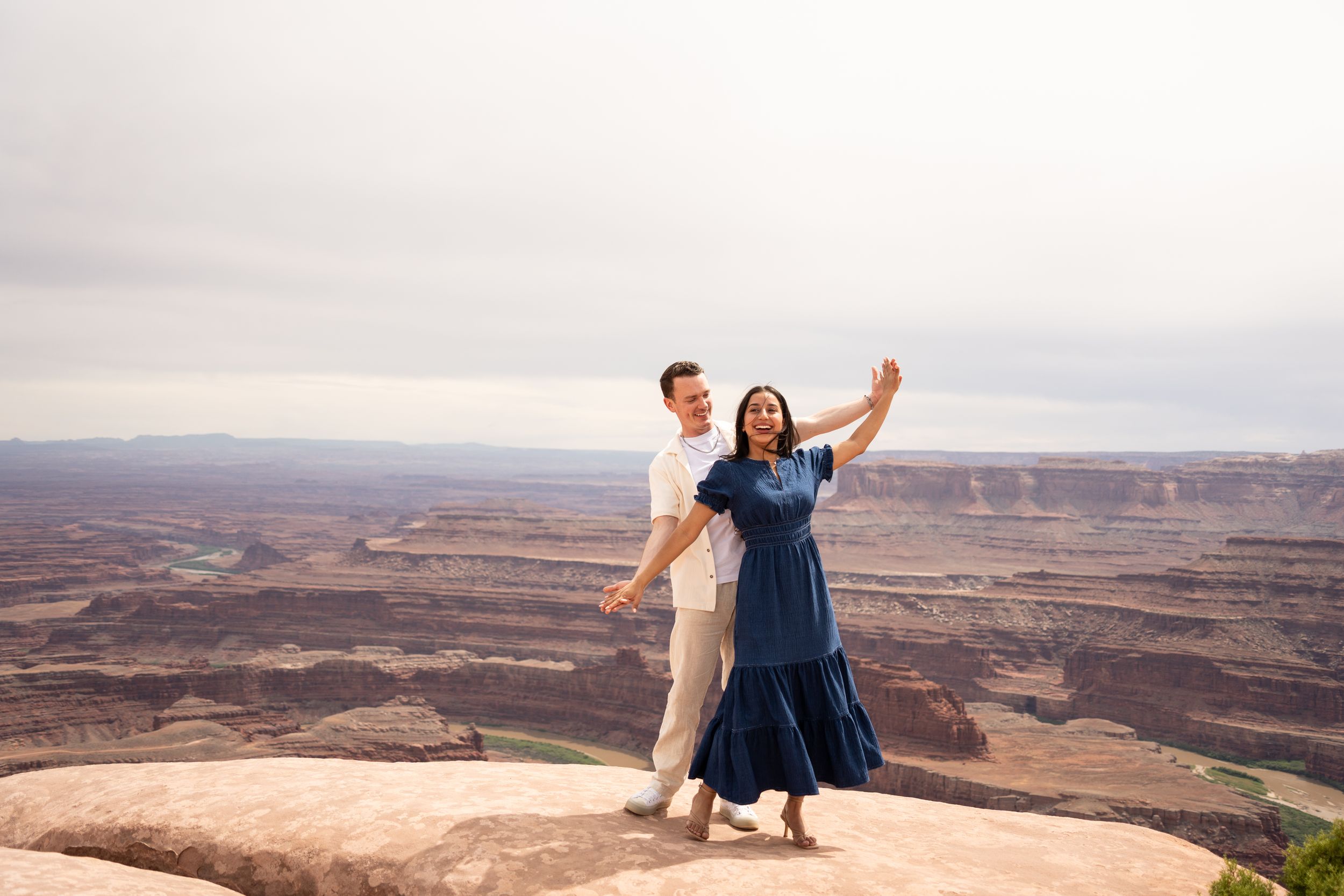 Couple dancing joyfully on a rocky overlook at Dead Horse Point State Park, one of the parks compared in this guide