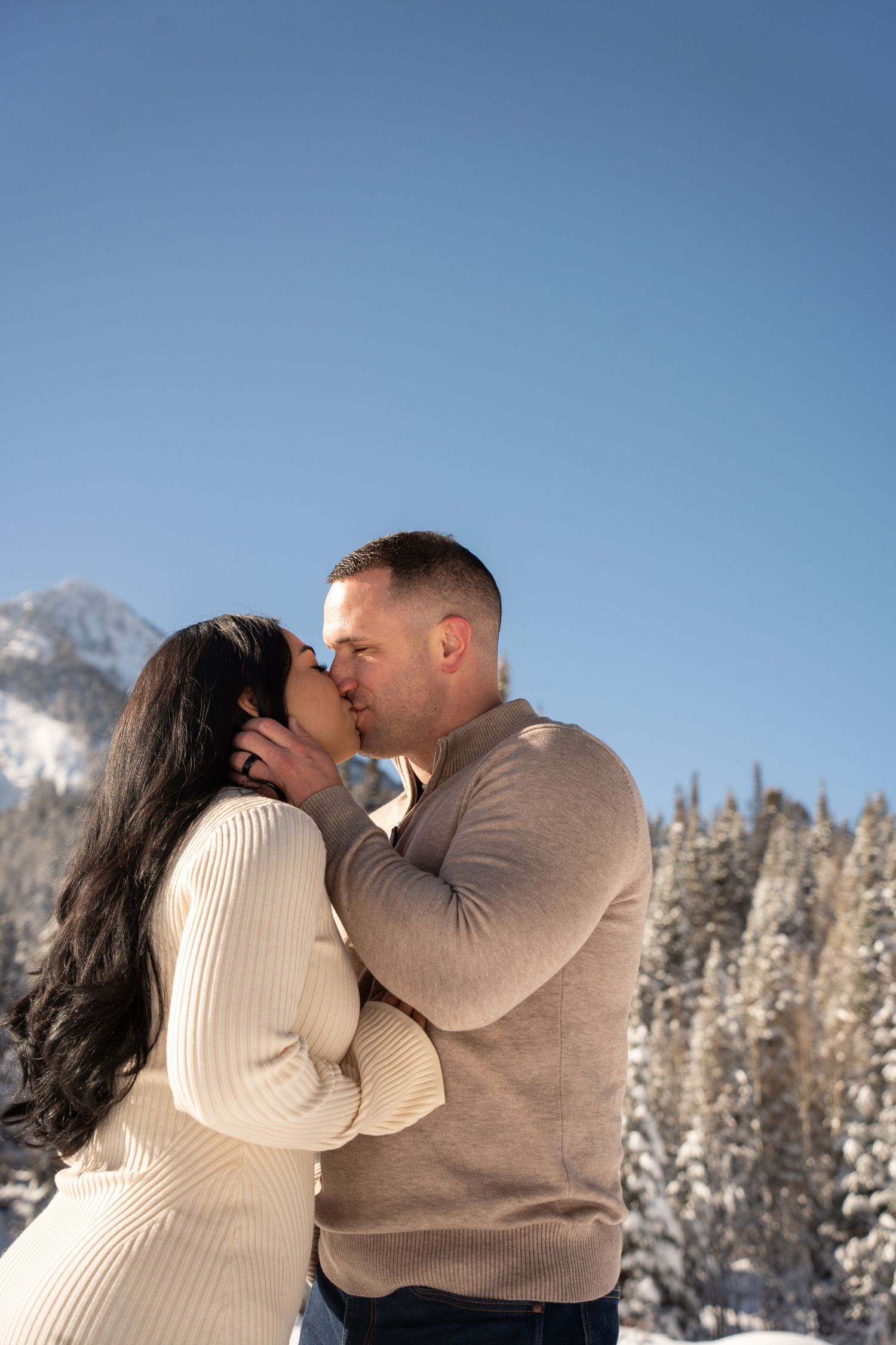 Couple sharing a romantic kiss in a snowy mountain landscape after their Brighton, Utah elopement