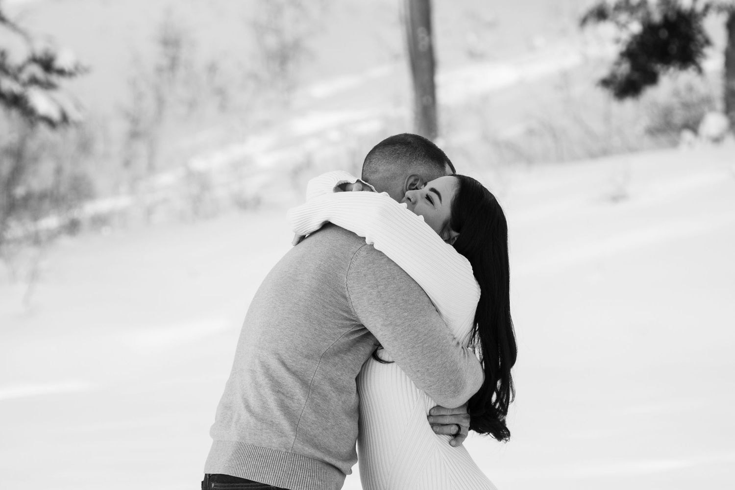 Couple embracing and kissing in a snowy winter landscape in Big Cottonwood Canyon, near Salt Lake City