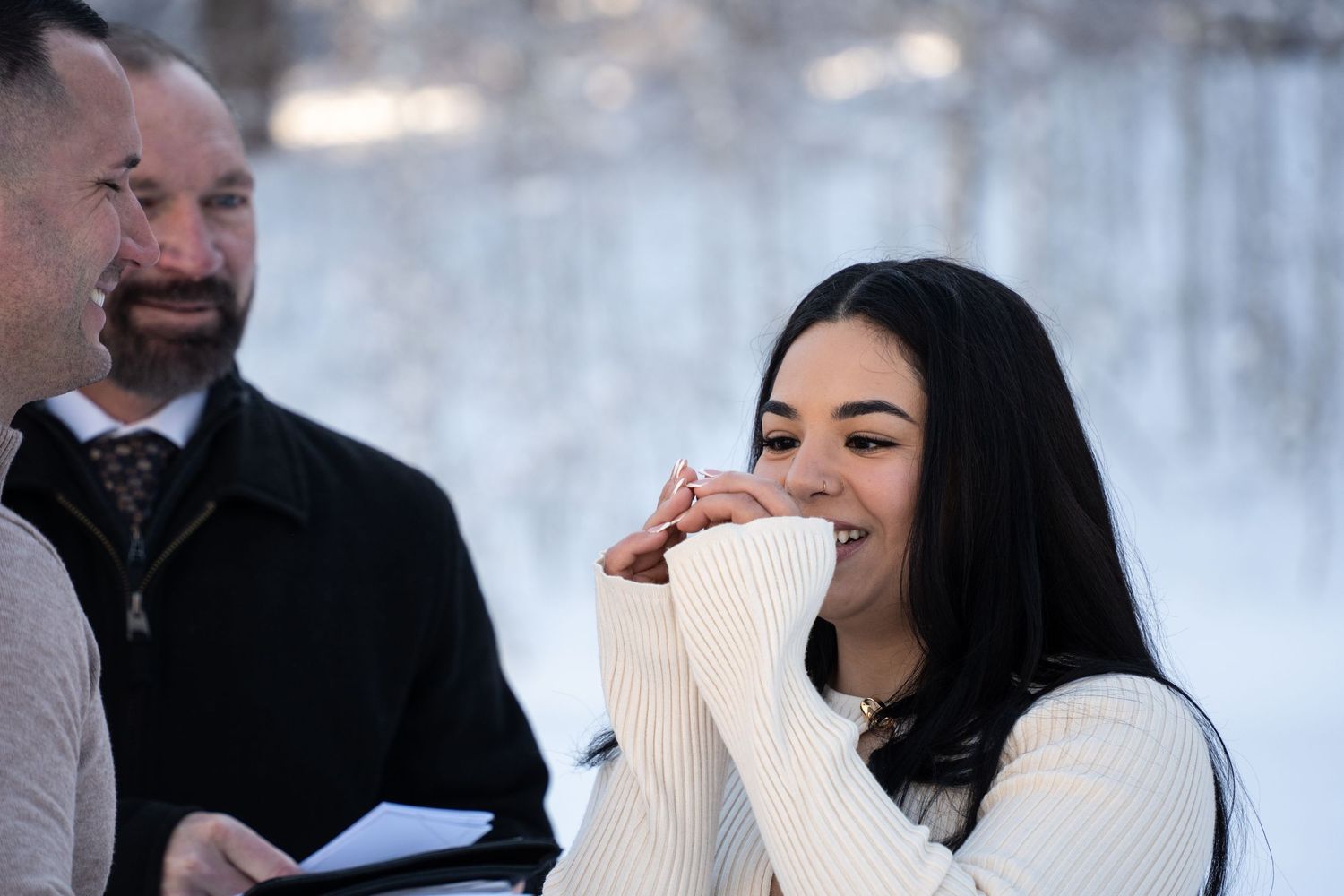Emotional bride in casual wedding dress inspecting her ring during outdoor winter wedding ceremony in Brighton Utah