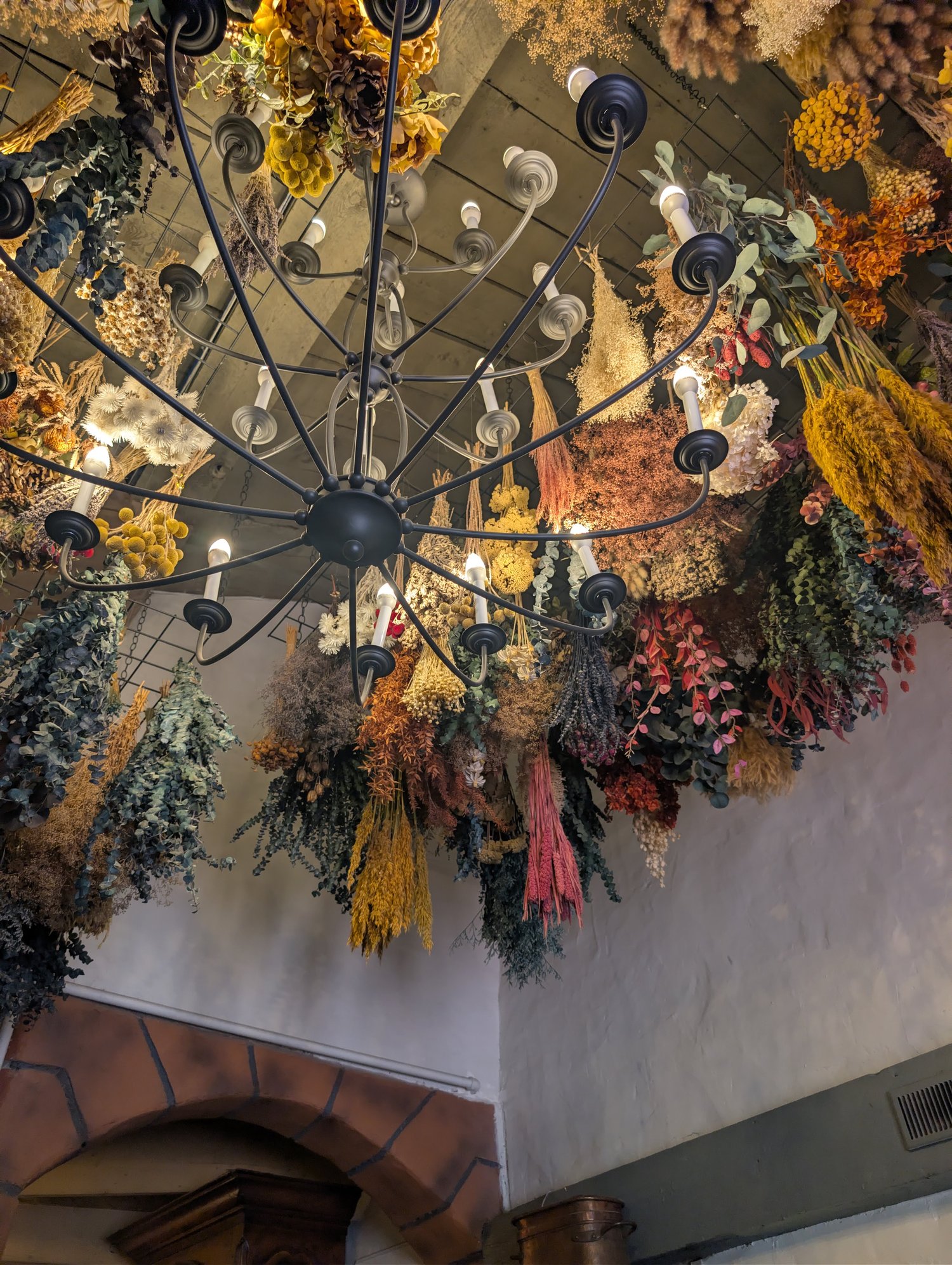 Dried flower and eucalyptus chandelier installation hanging over La Caille's restaurant entryway