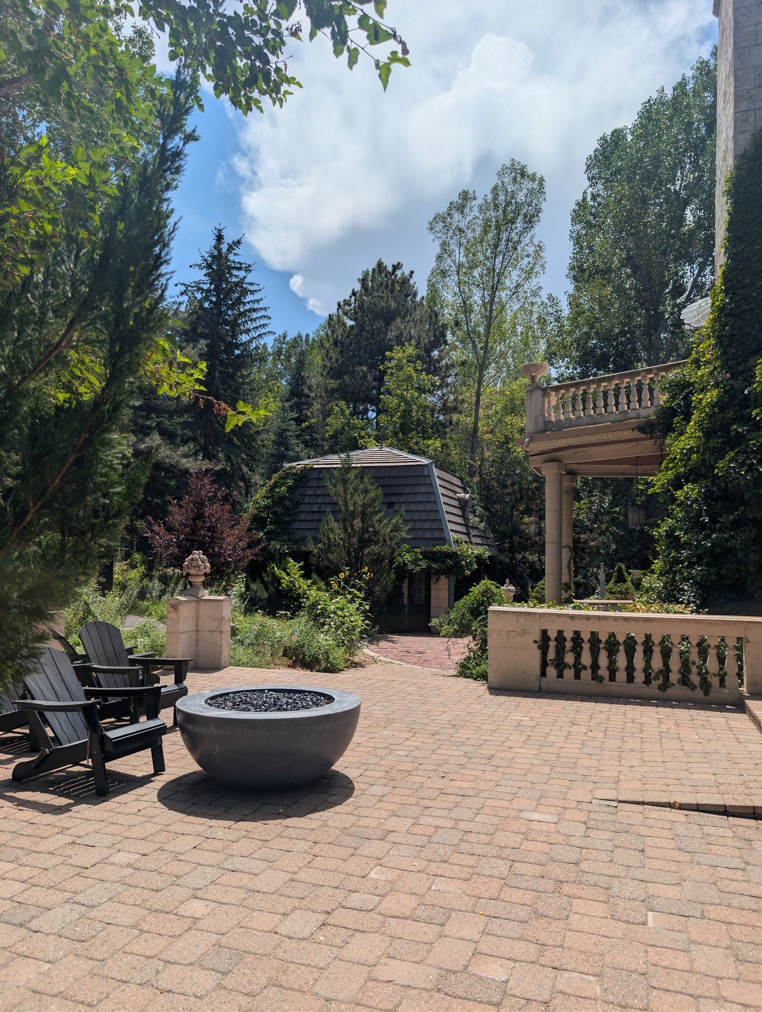 Brick patio with a black fire pit and Adirondack chairs on the Chateau's deck at La Caille