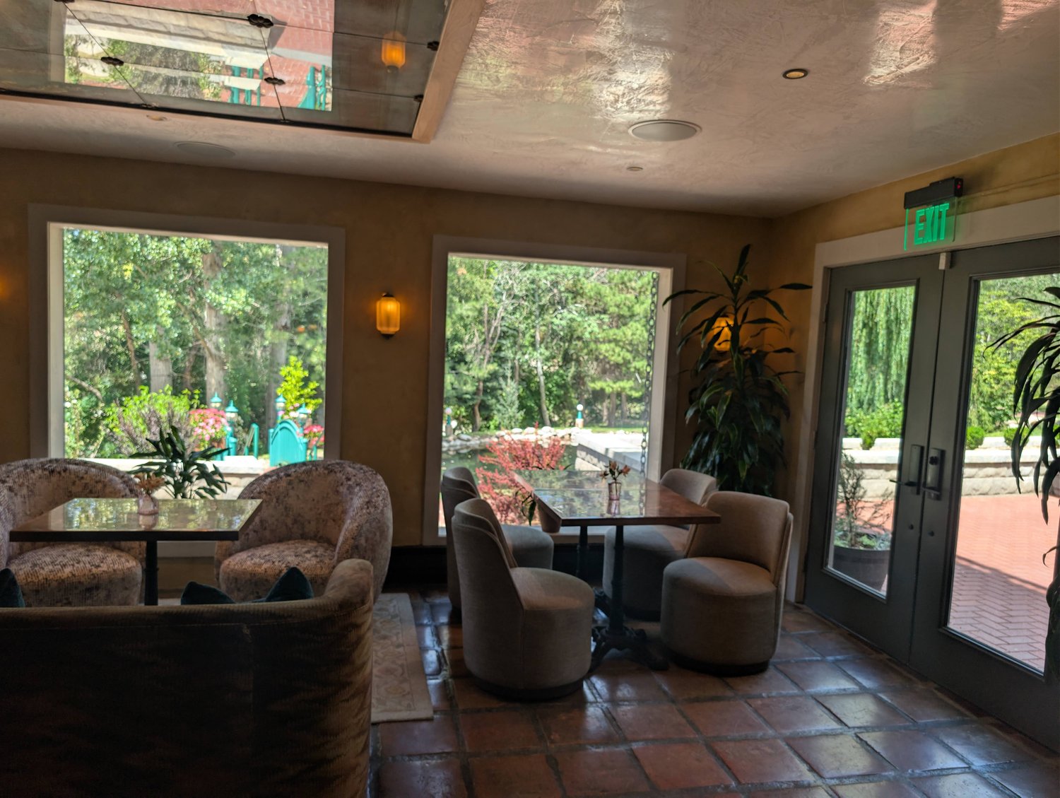 Cozy seating area at Les Secrets with round tables and large windows looking out onto the garden