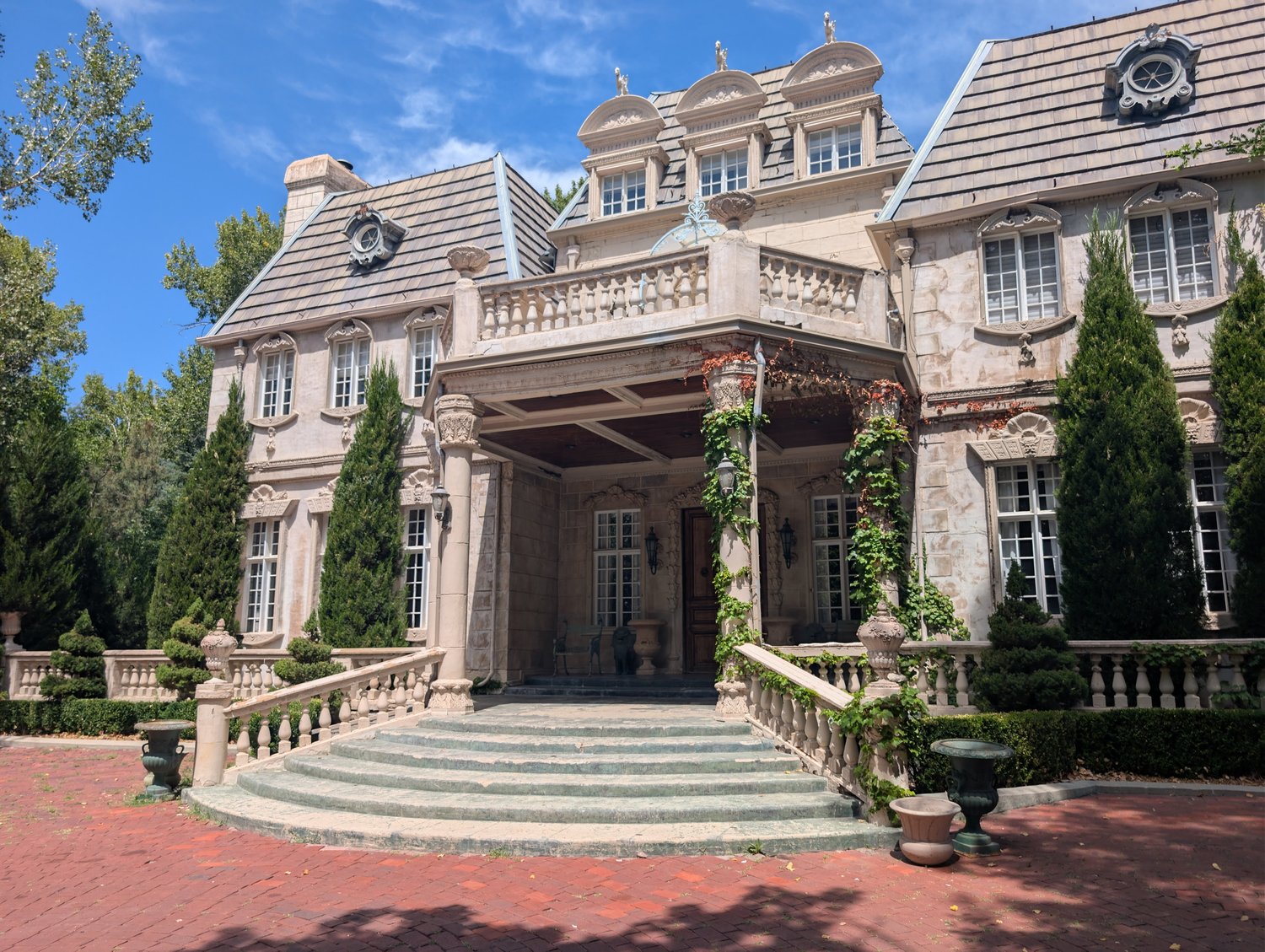 Grand French-style stone chateau entrance at La Caille, with curved stone steps and ivy-covered columns