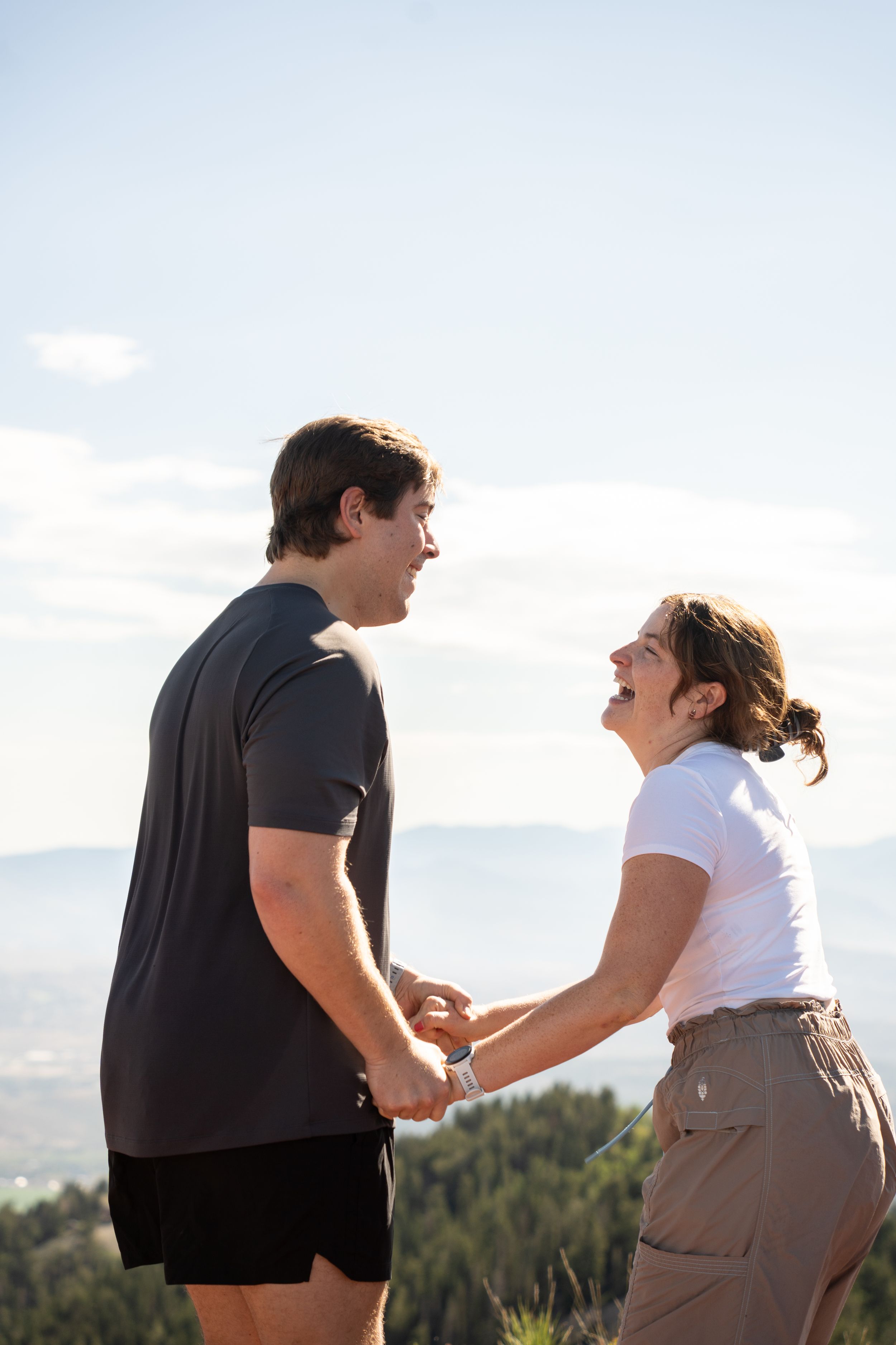 Couple holding hands and laughing together on a mountain ridge trail