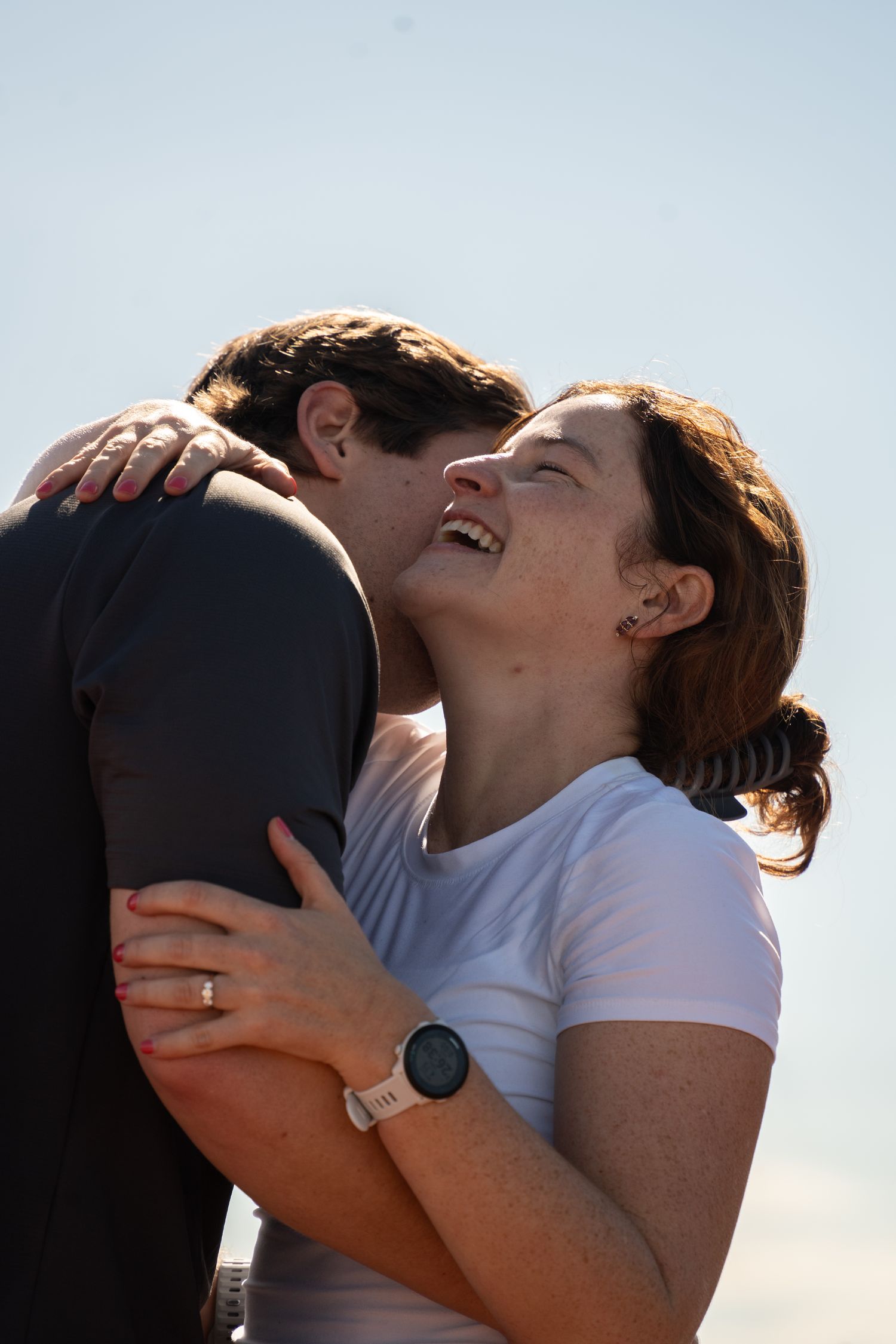 Man kneeling to propose to woman on a mountain ridge with the valley spread out behind him