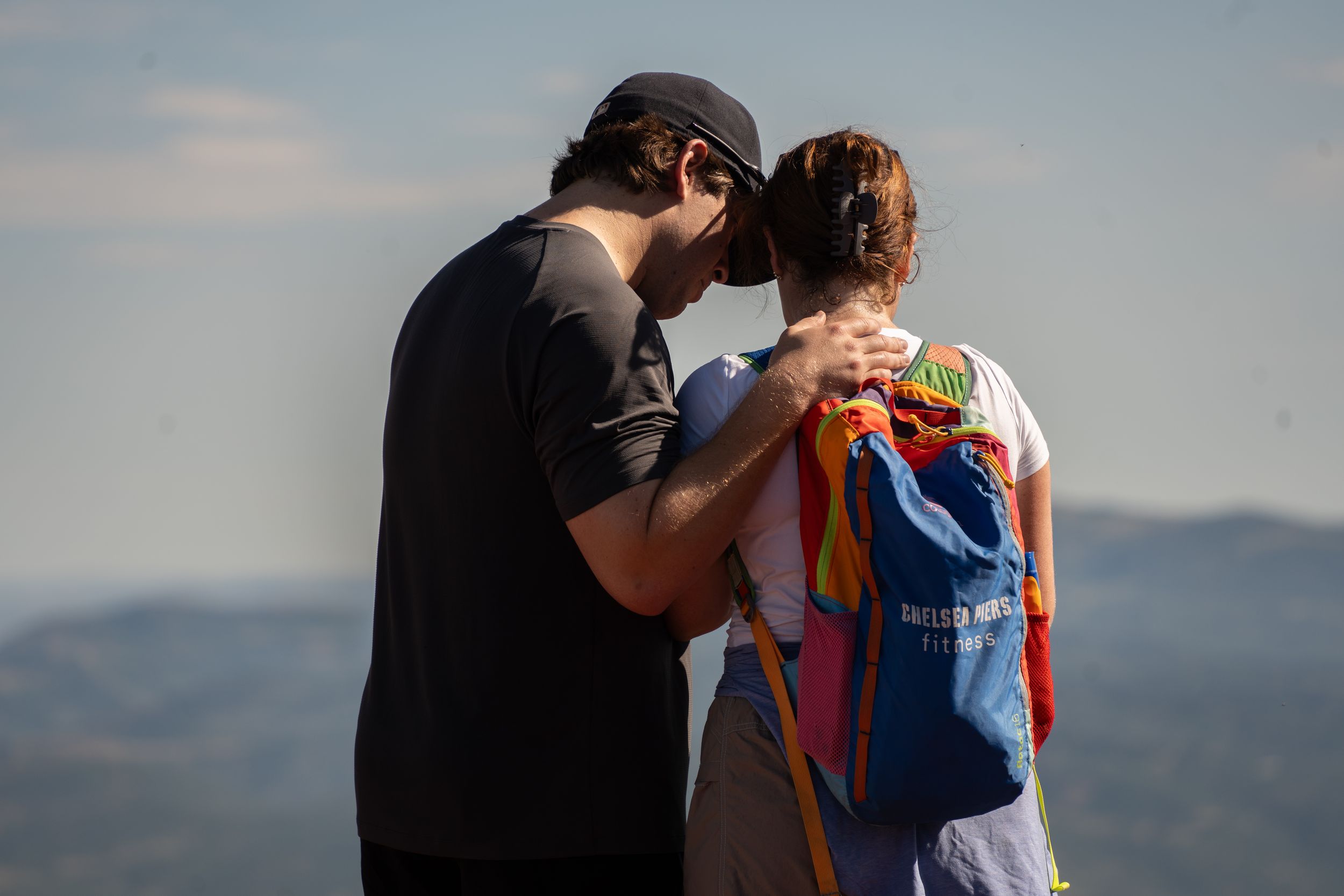 Newly engaged couple embracing and kissing at the edge of a mountain lake