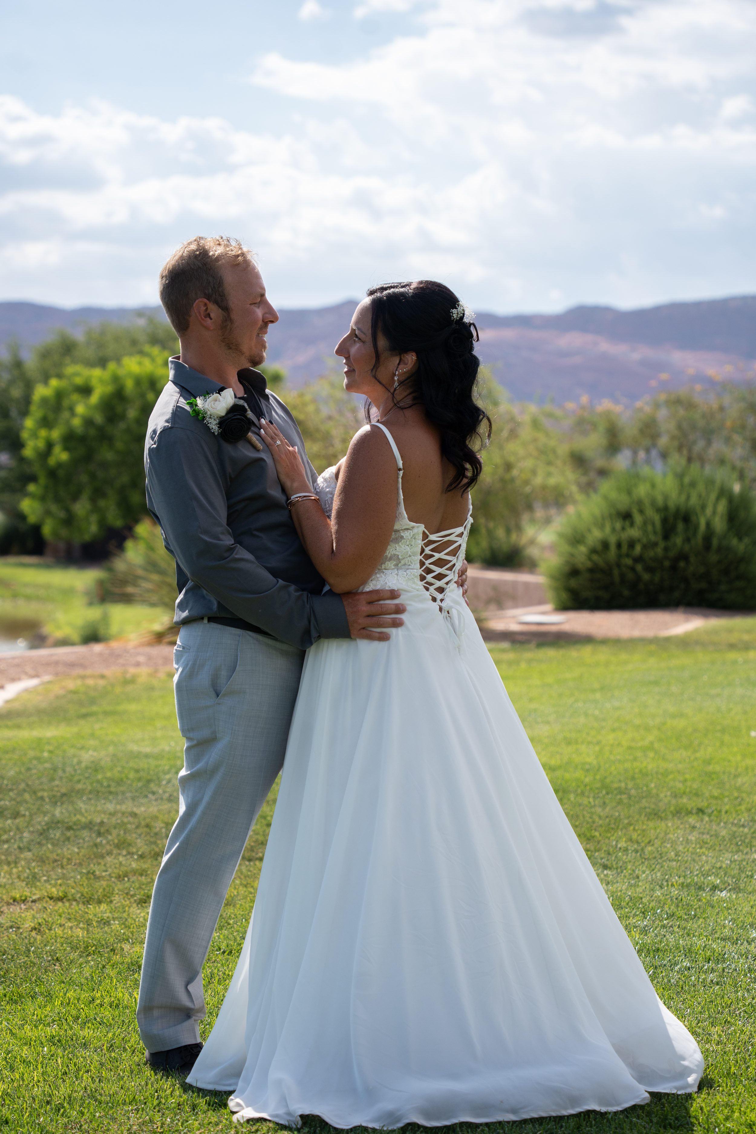 Bride and groom embracing on the lawn at The Ledges in St. George with red mountains in the background.