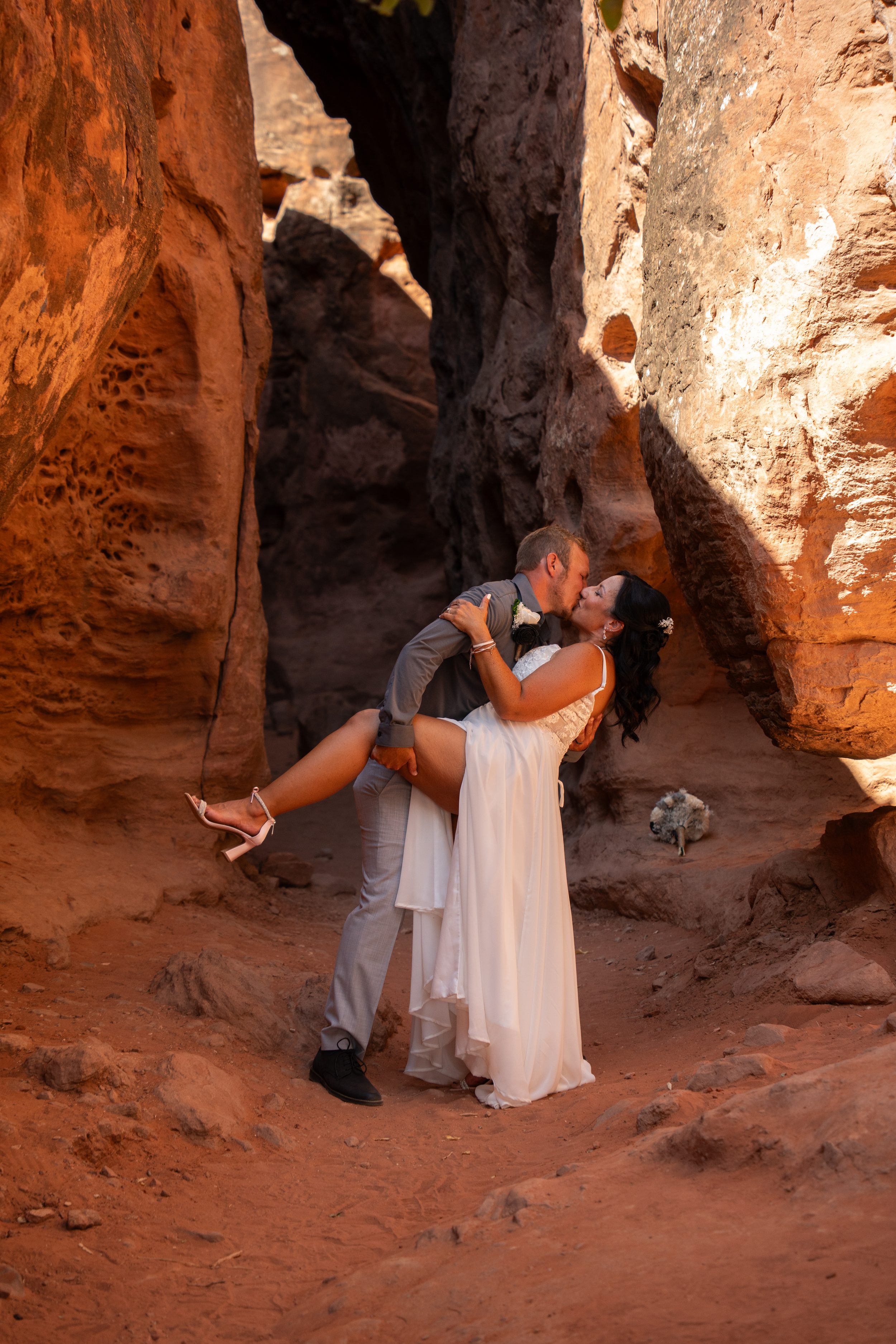 Groom dipping bride for a kiss inside a narrow slot canyon at Pioneer Park in St. George.