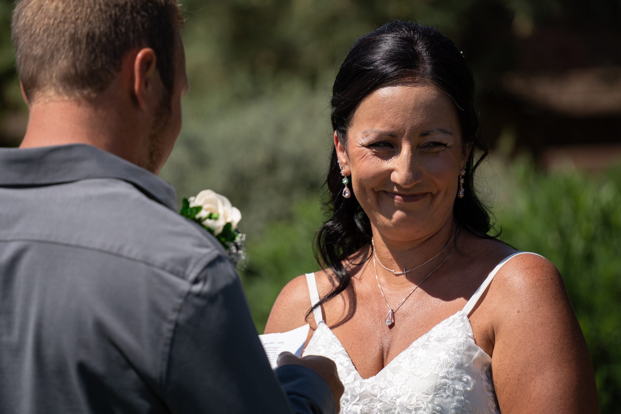 Bride reading her handwritten vows to the groom during their outdoor ceremony.