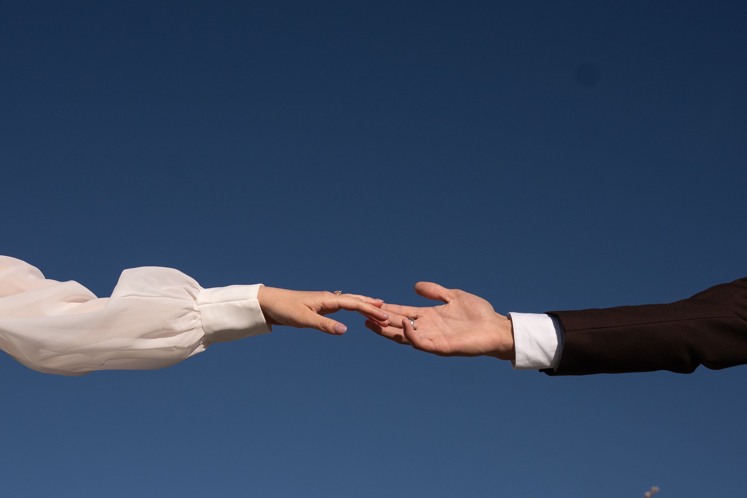 Two hands of bride and groom reaching toward each other