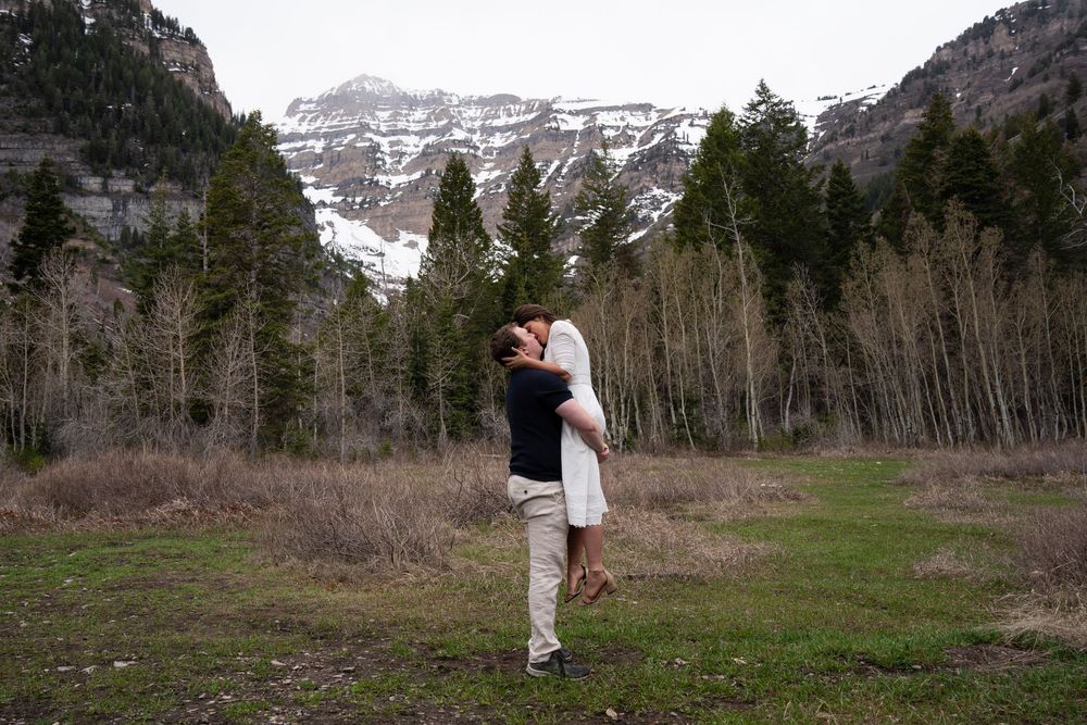 Couple embracing in a mountain meadow with snow-capped peaks