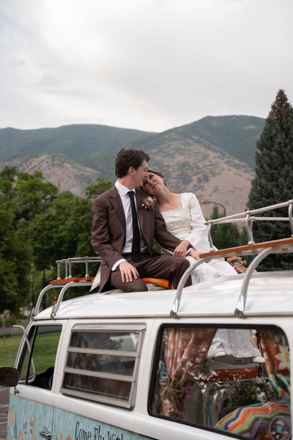 Bride and groom share a romantic moment atop a vintage VW bus