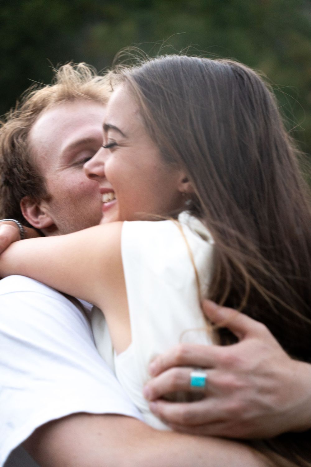 A happy young couple sharing a warm embrace and smile outdoors