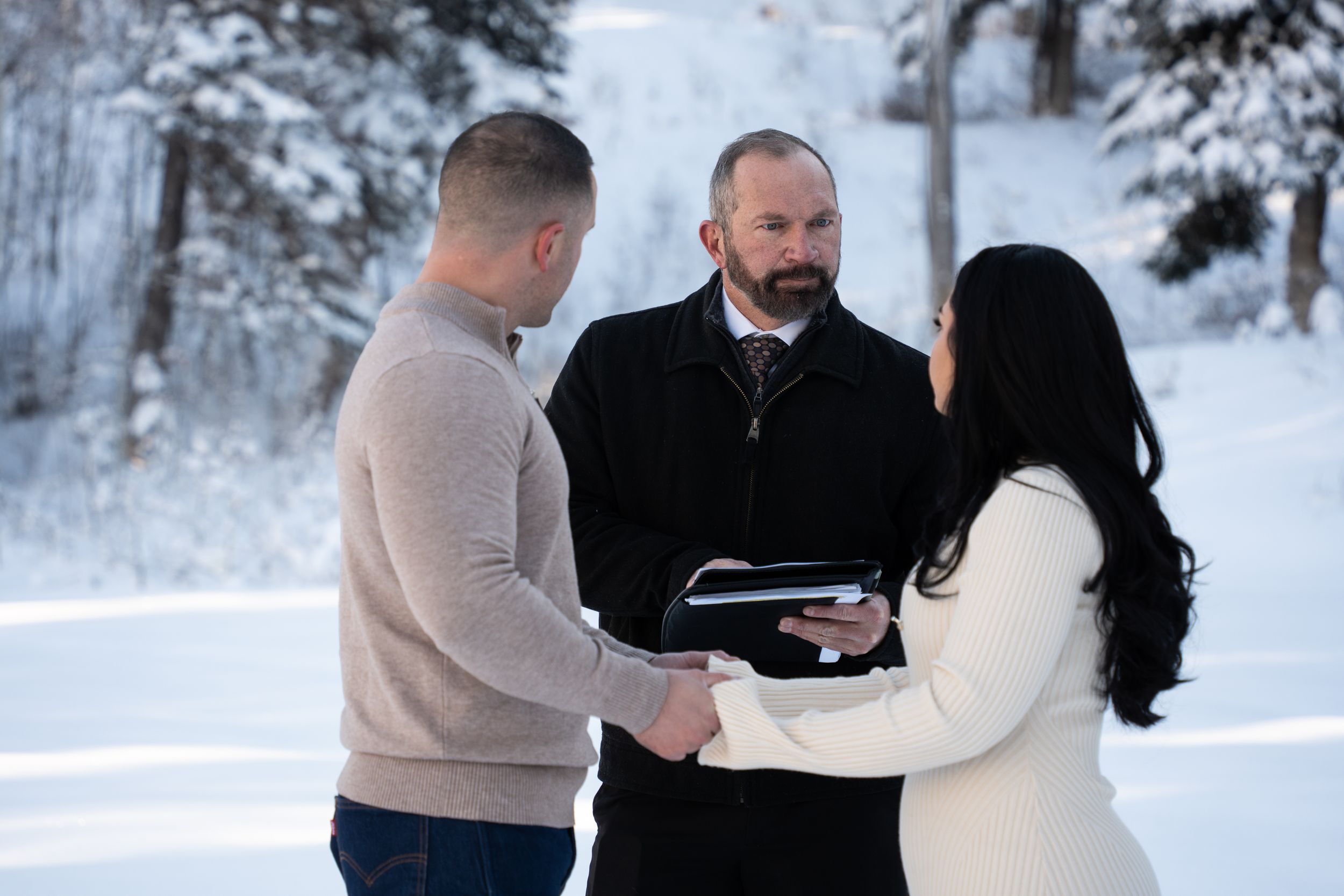 Couple exchanging vows in a snowy winter outdoor wedding ceremony