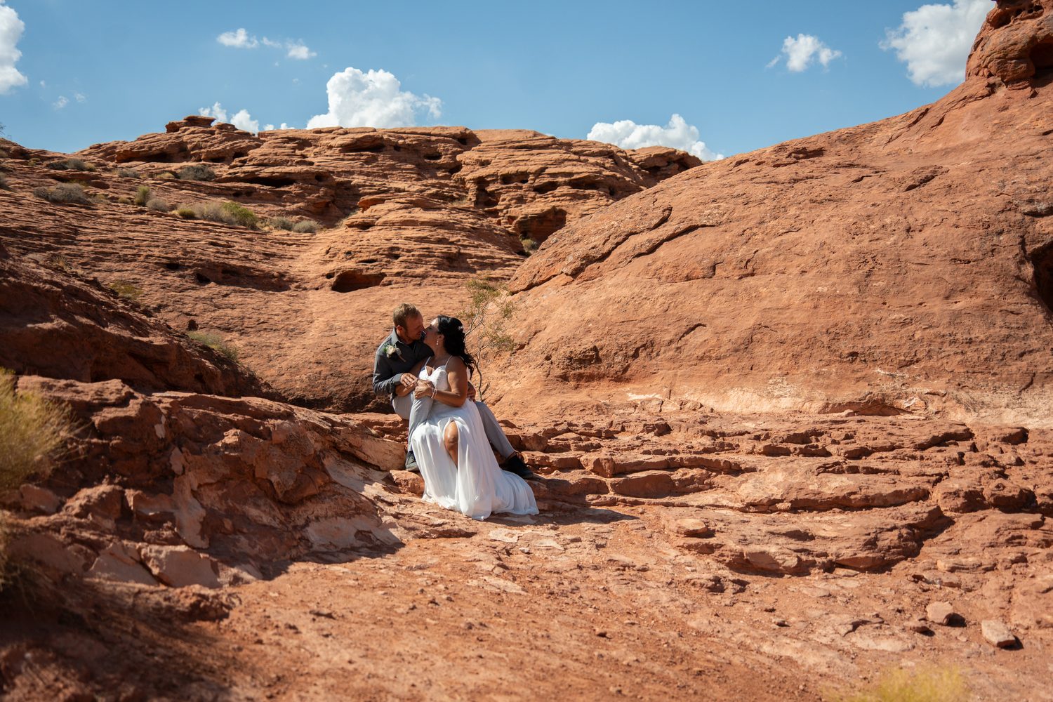 Bride and groom embracing on red rock terrain near St. George, Utah