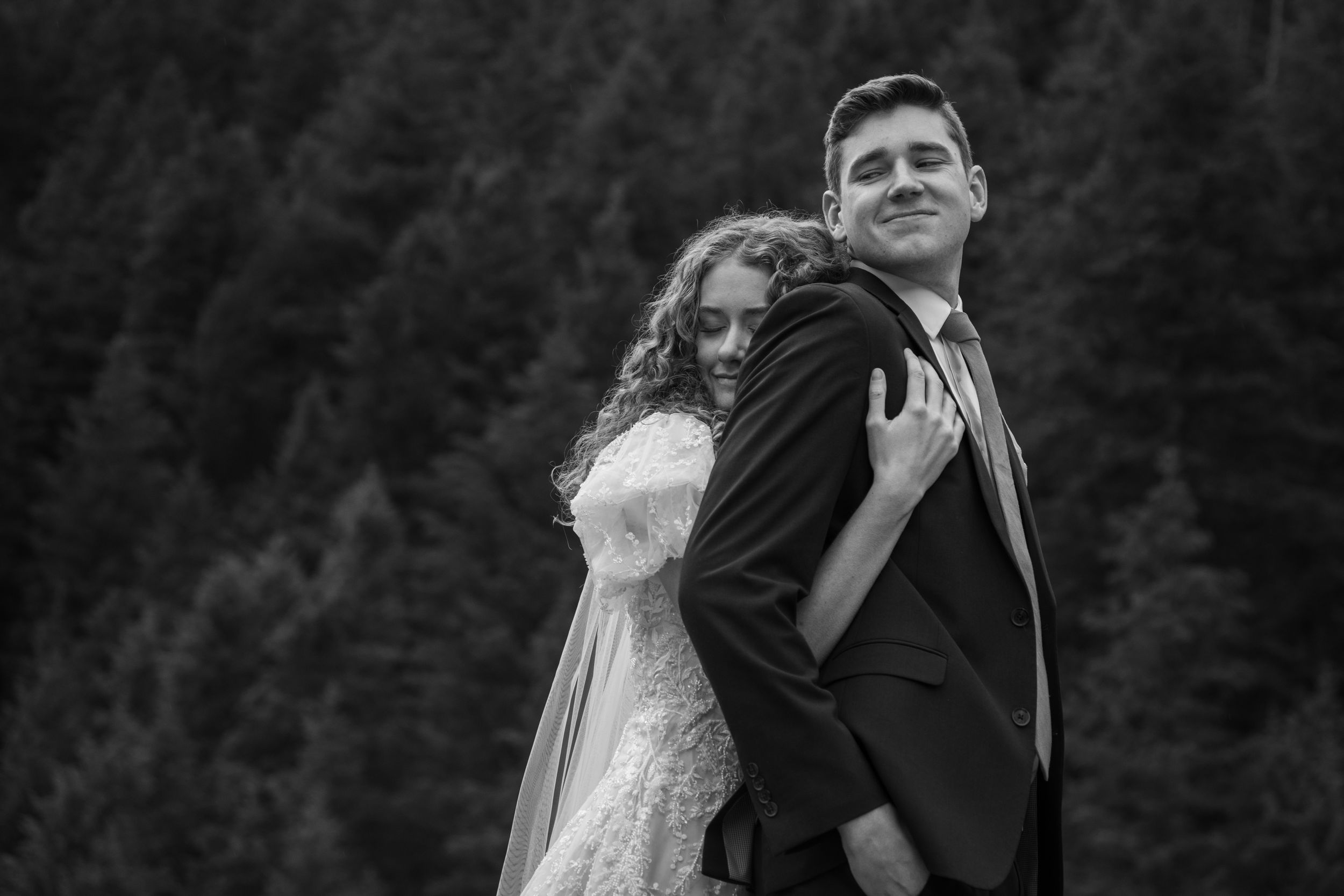 Bride embraces groom in snowy Provo Canyon forest during bridal portraits before their wedding